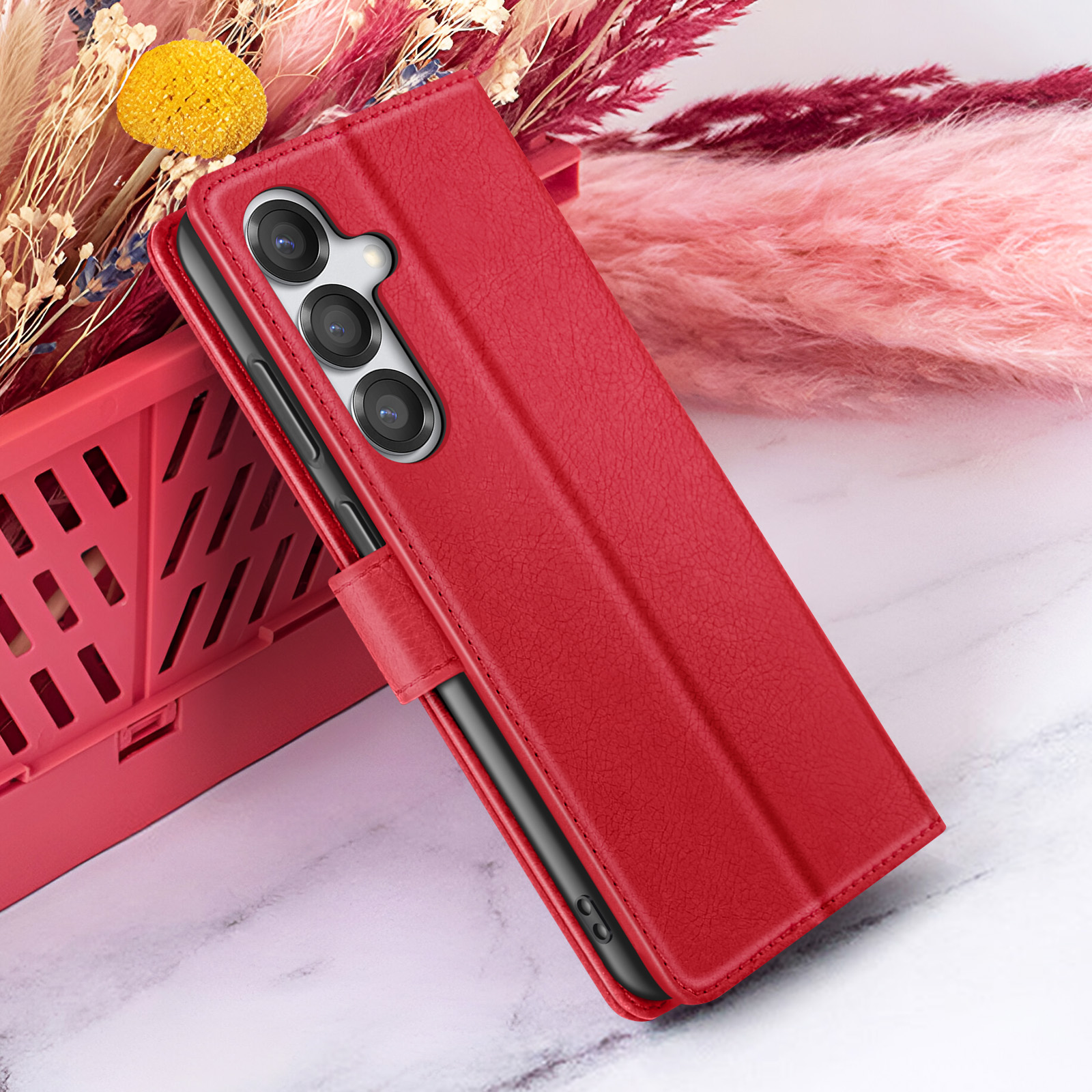 Rode telefoonhoes met telefoon. Achter, een rode mand en bloemen van verschillende kleuren. Op marmer.
