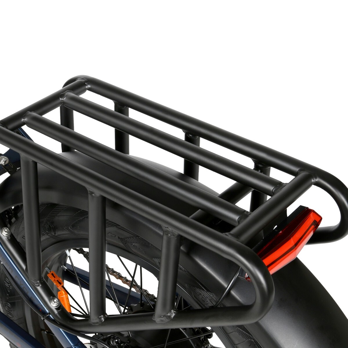 Zbliżenie czarnego bagażnika rowerowego na rowerze. Widoczny jest czerwony odblask. Rower ma czarne błotniki i koło.