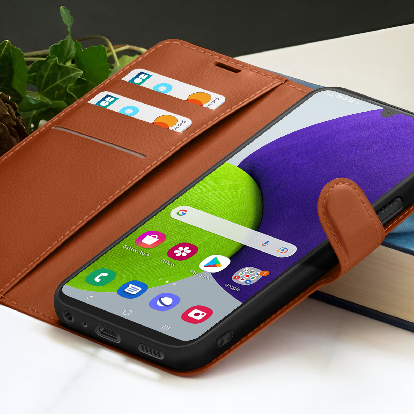 Een smartphone met een groen en paars scherm in een bruine lederen hoes. Kaarten in een gleuf. Een boek op de achtergrond.