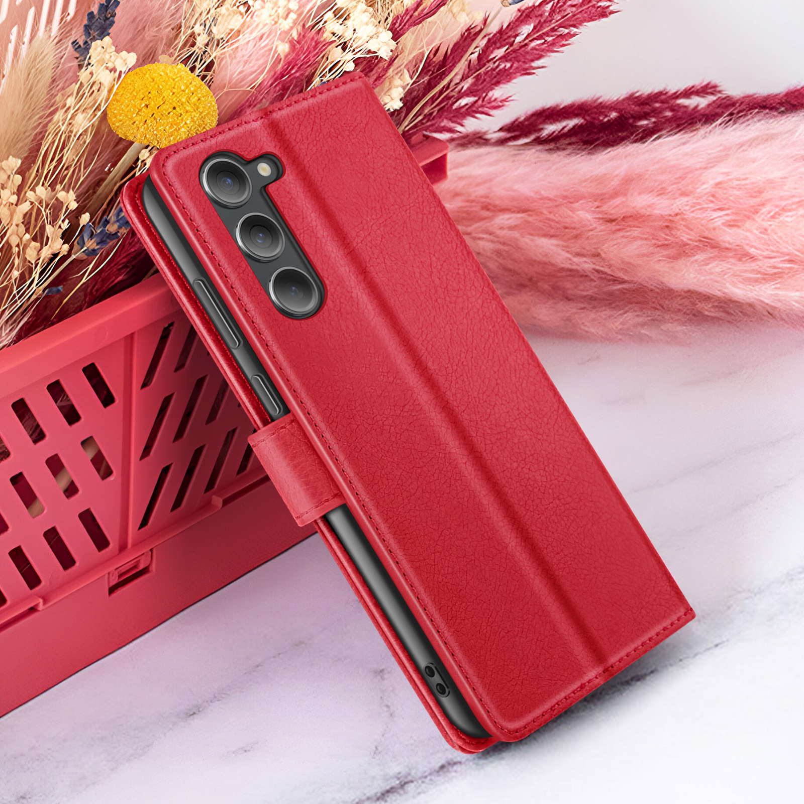 Étui de téléphone rouge avec triple caméra, panier rouge et fleurs séchées.