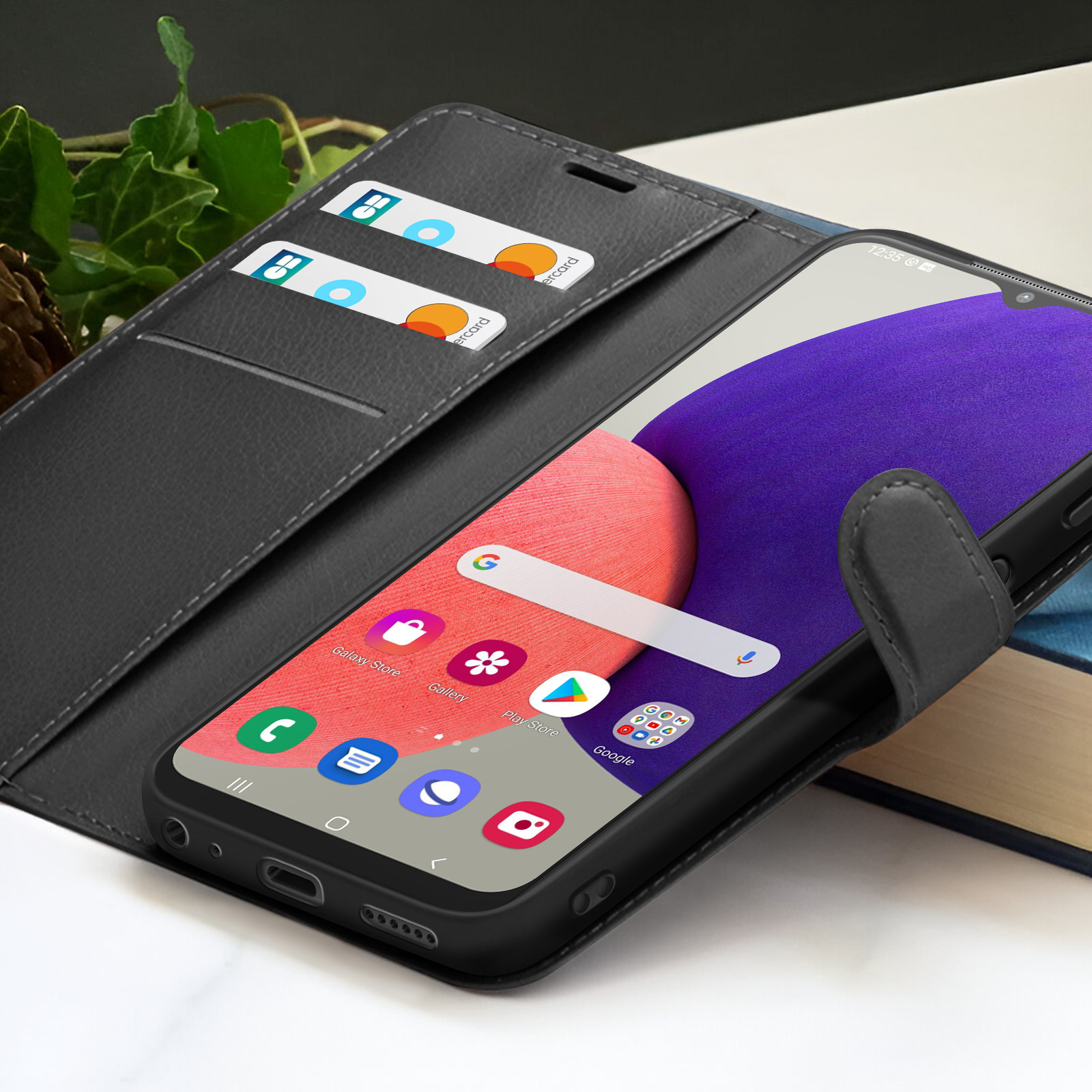 Een zwarte telefoon in een portemonnee-etui toont app-iconen. Creditcards zitten in de etui. Paarse en roze achtergrond op het scherm.