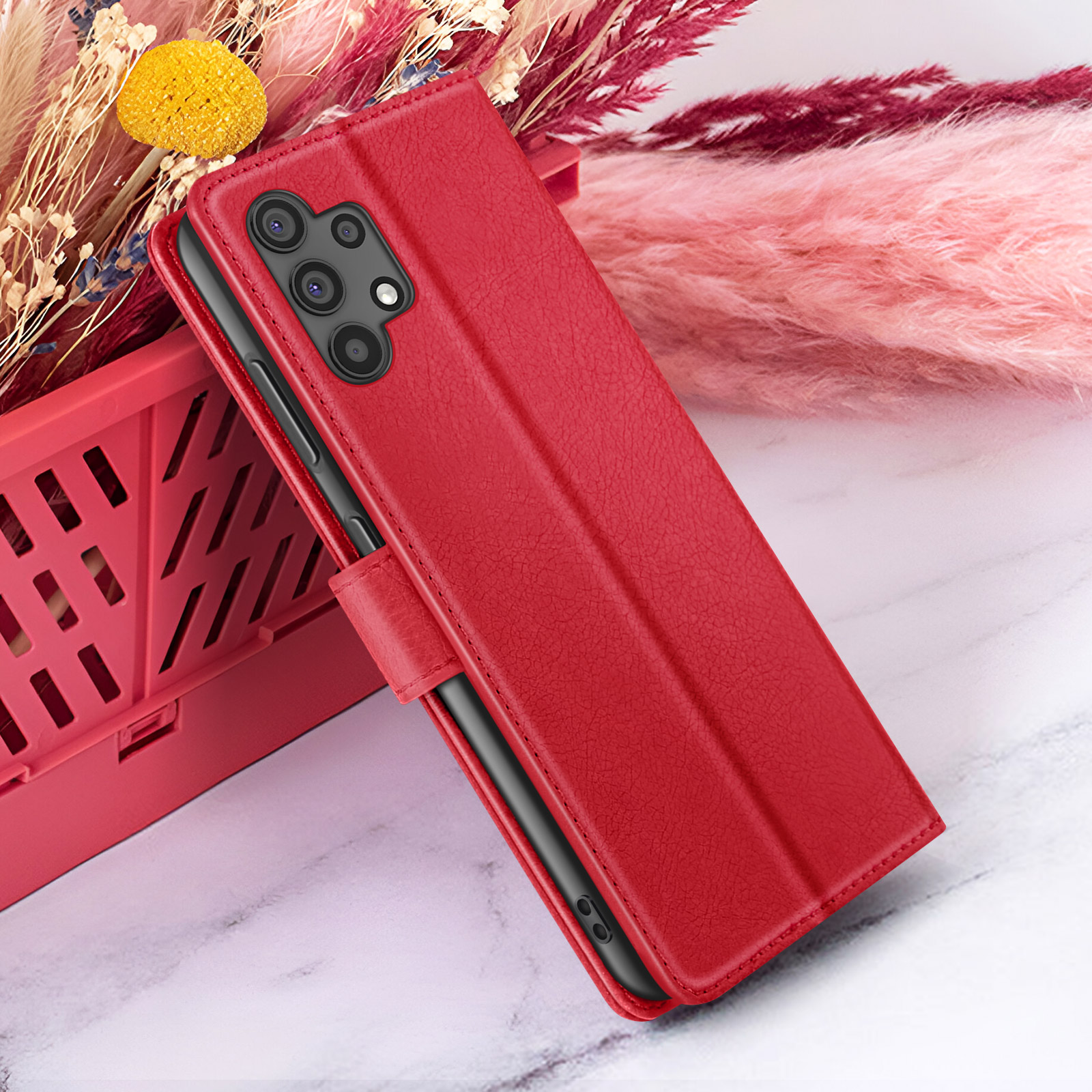 Een rode telefoonhoes is open en onthult een zwarte telefoon. Het ligt op een marmeren oppervlak, met bloemen op de achtergrond.
