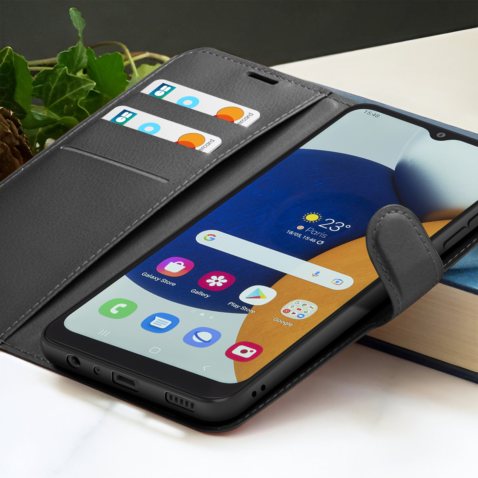 Een zwarte smartphone in een grijze hoes toont tijd, weer en app-pictogrammen. Er zitten creditcards in de hoes.