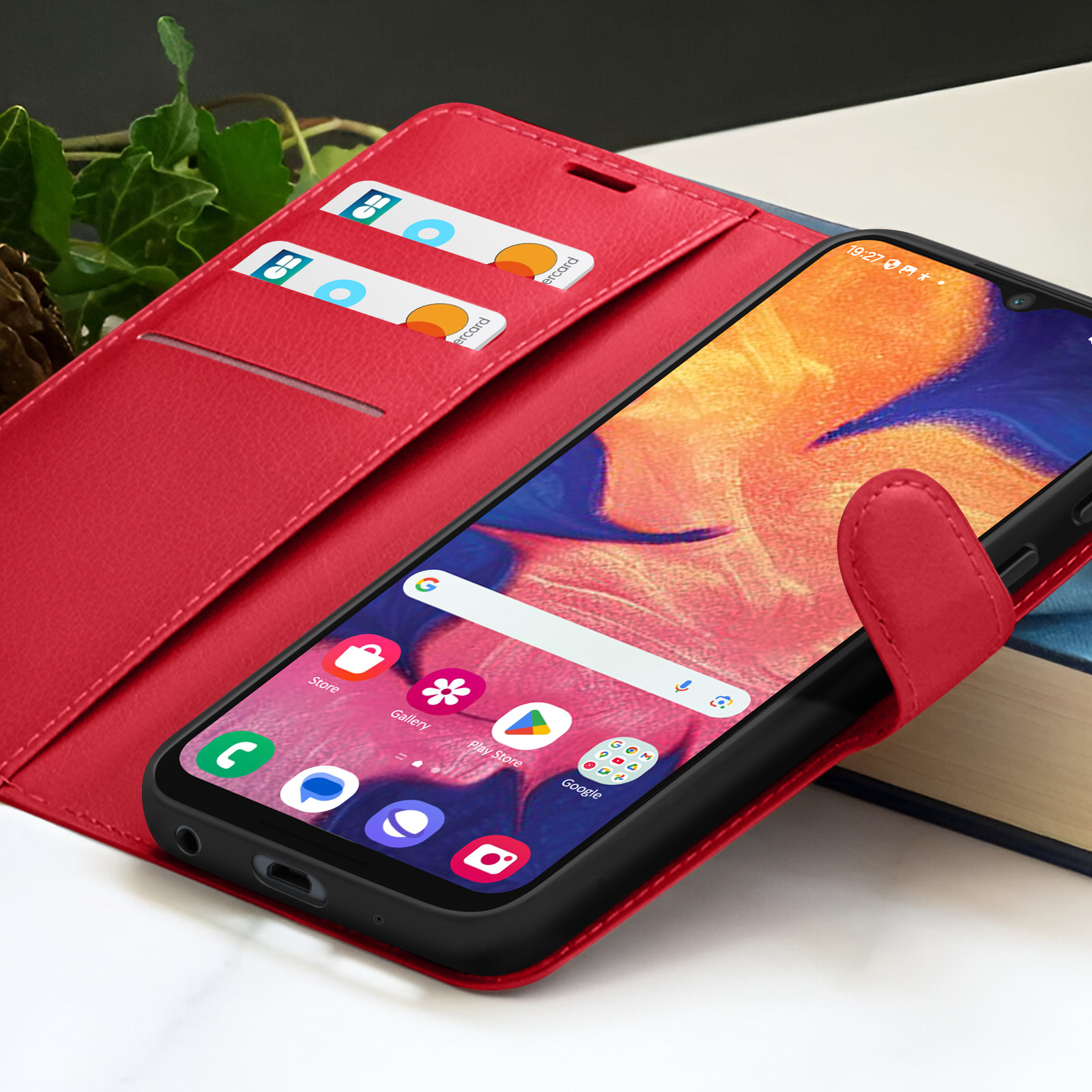Custodia rossa con telefono all'interno. Due carte sono visibili nella custodia. Il telefono mostra la schermata iniziale.