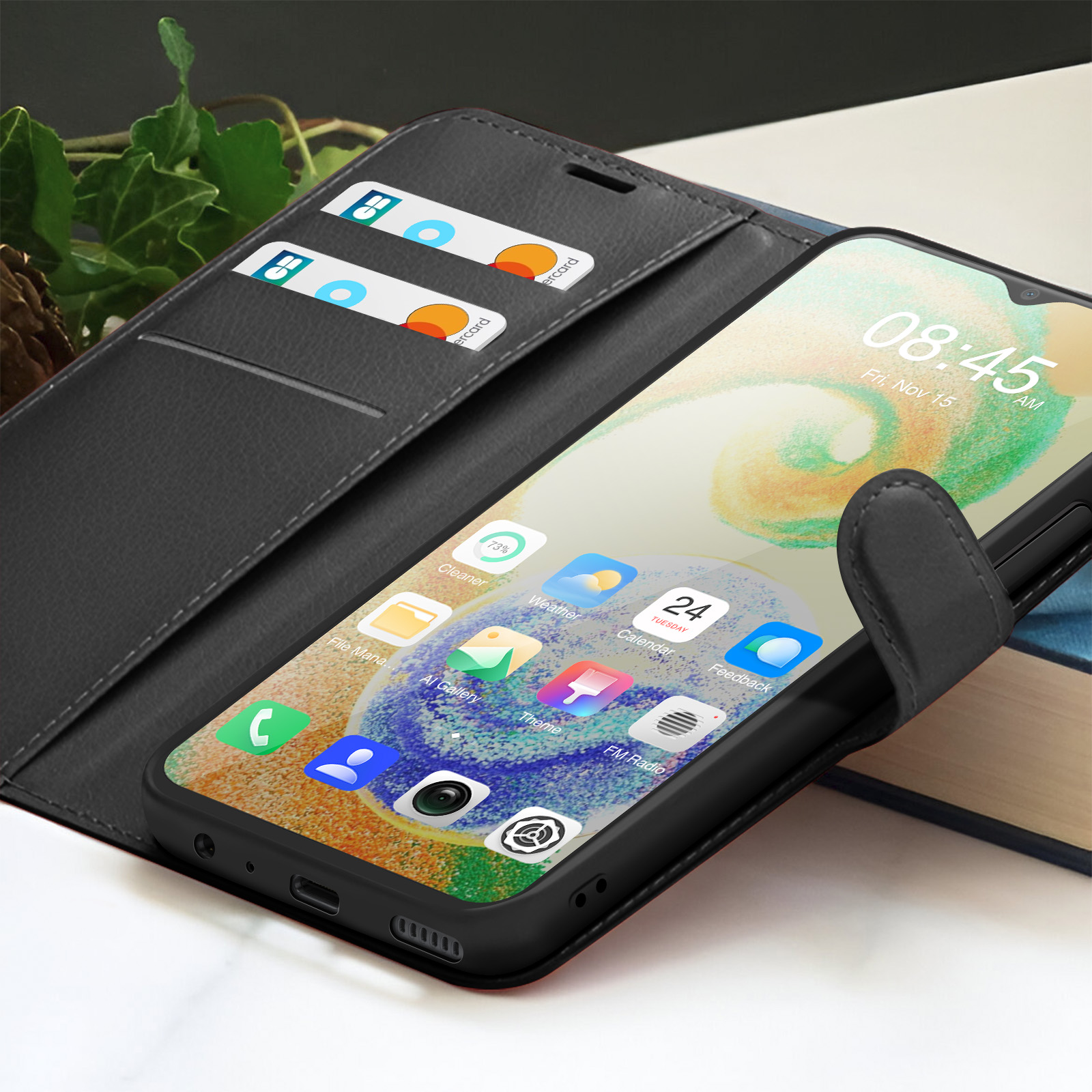 Un telefono nero in una custodia mostra app e ora. Due carte di credito sono in una tasca. La custodia è aperta.