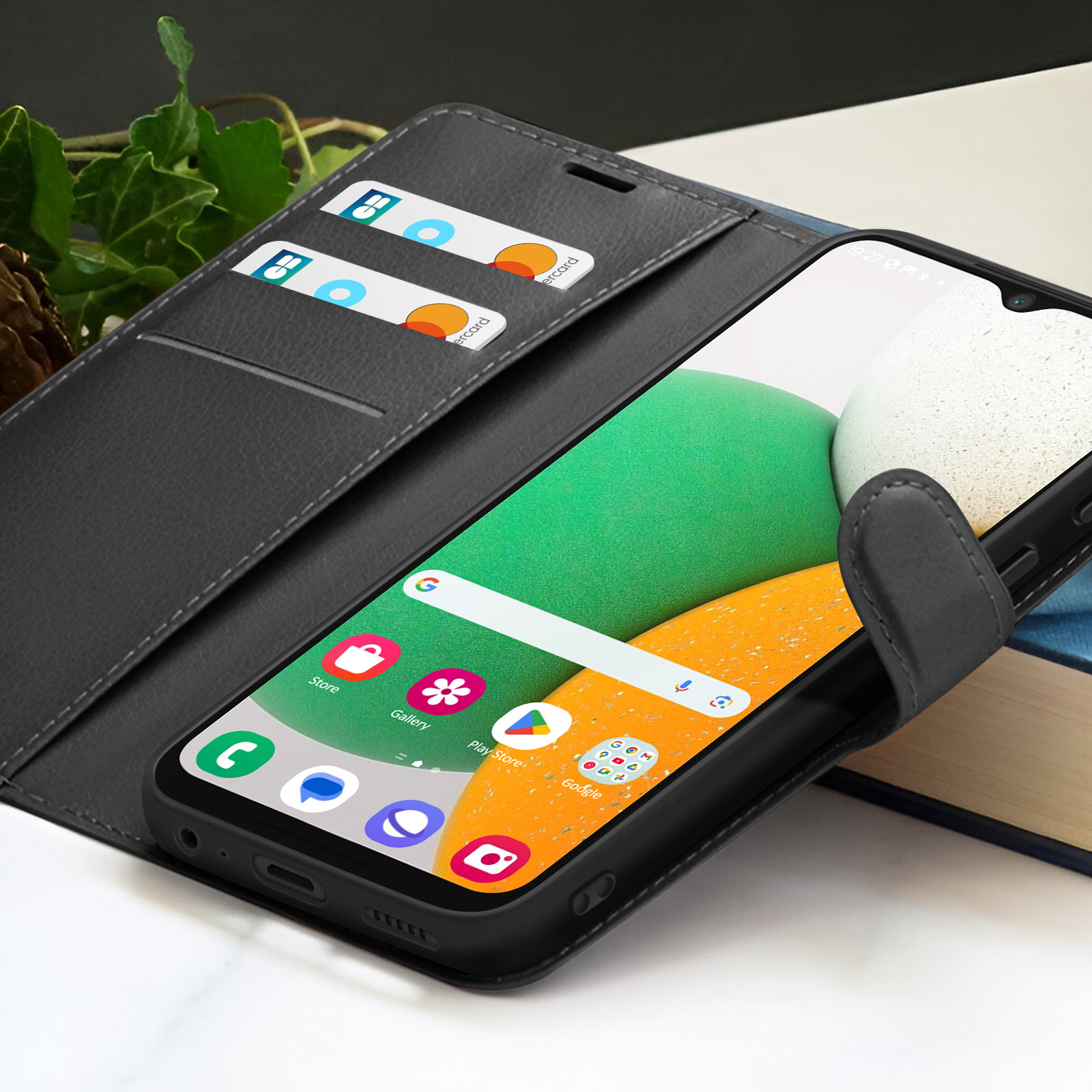 Un telefono nero in una custodia a portafoglio con carte di credito. Il telefono mostra la schermata iniziale con icone di app.