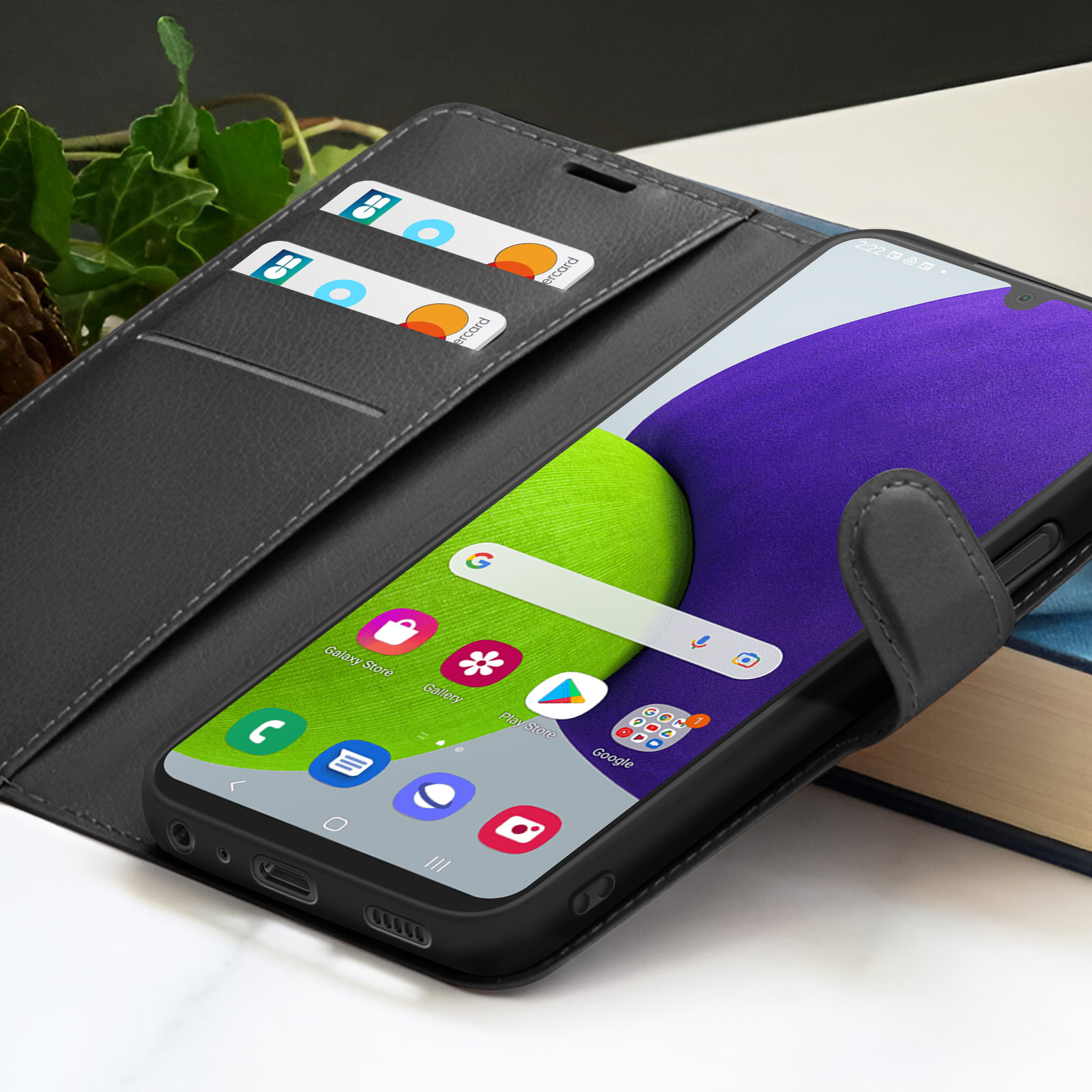 Een smartphone in een zwarte case met een portemonnee-ontwerp. Het scherm toont app-iconen. Creditcards zijn zichtbaar in de case.