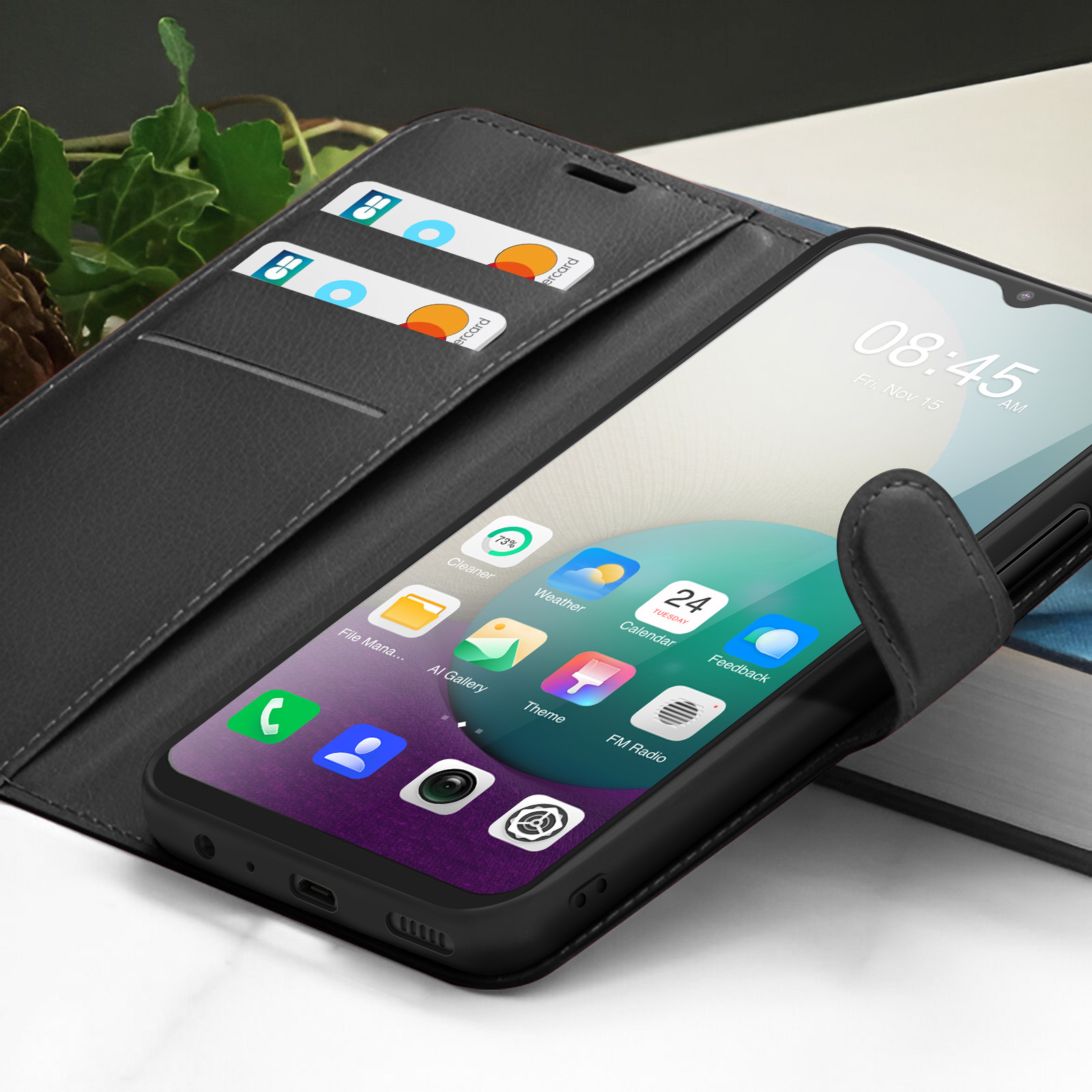 Un téléphone noir dans un étui portefeuille affiche l'heure et les icônes des applications. Des cartes de crédit sont dans l'étui. L'arrière-plan comprend un livre.