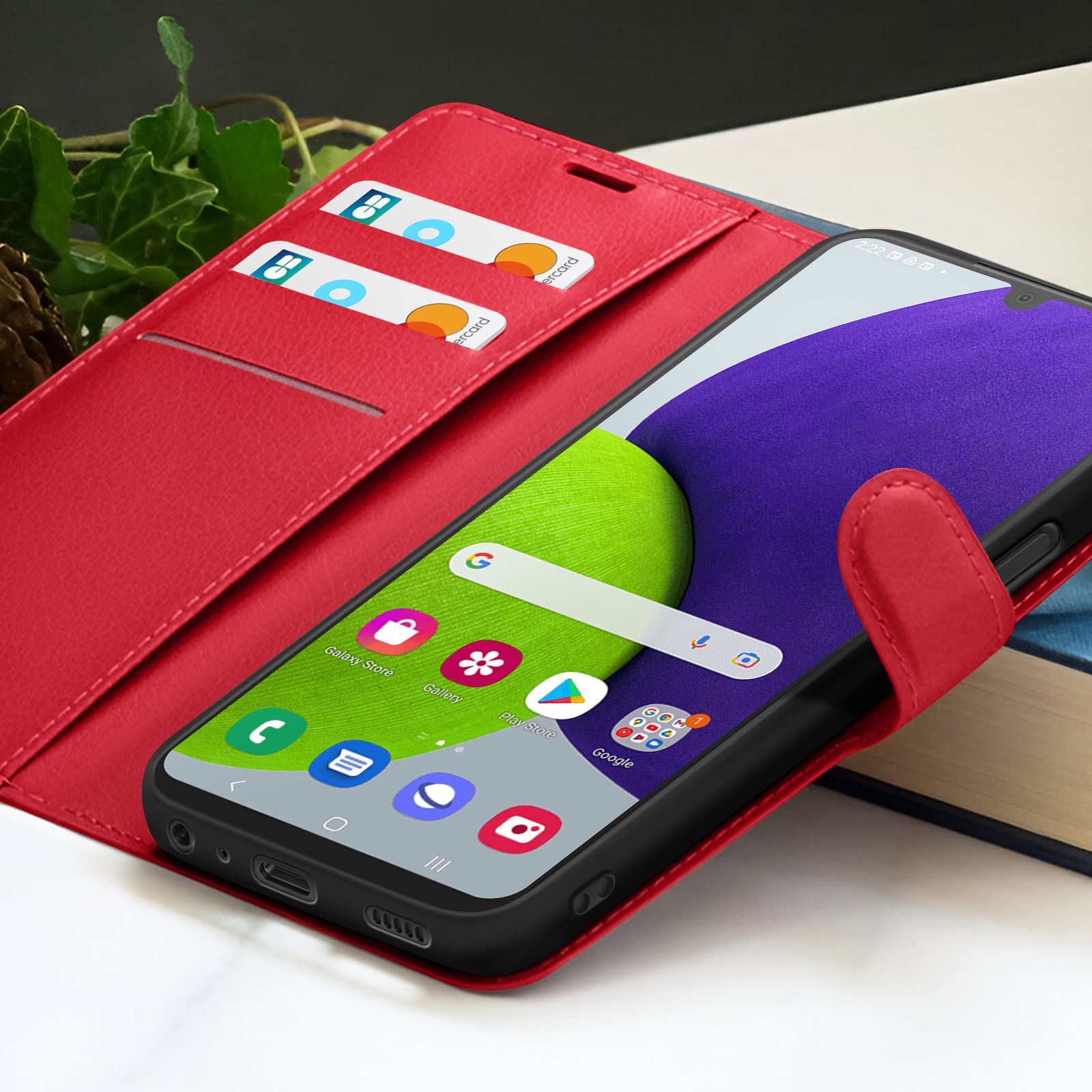 Rode telefoonhoes met telefoon met apps, creditcards in een sleuf. Achtergrond heeft klimop en een boek.