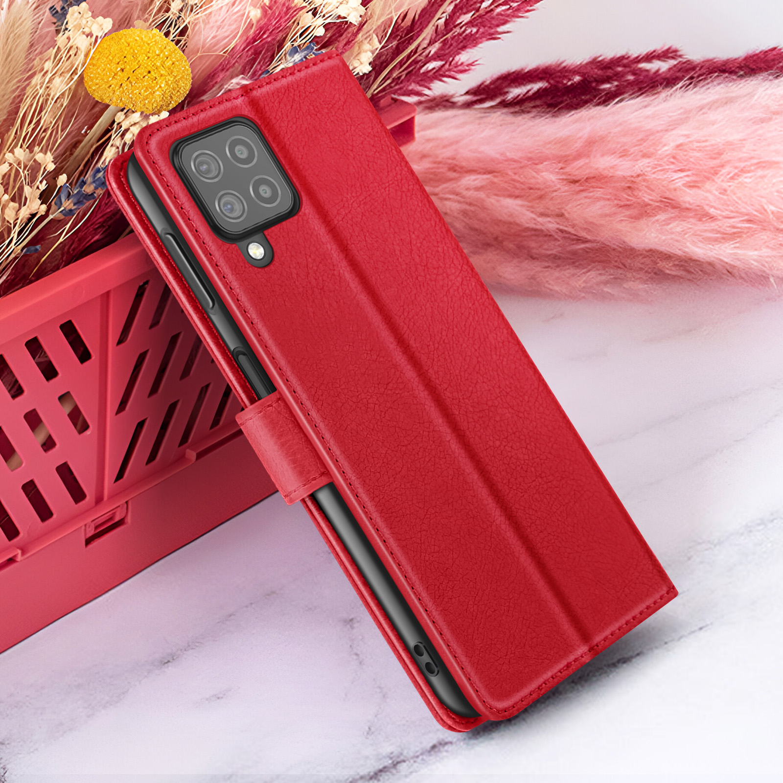 Rode telefoonhoes met camera, open. Roze en paarse bloemen op de achtergrond. Marmeren oppervlak en rode mand.