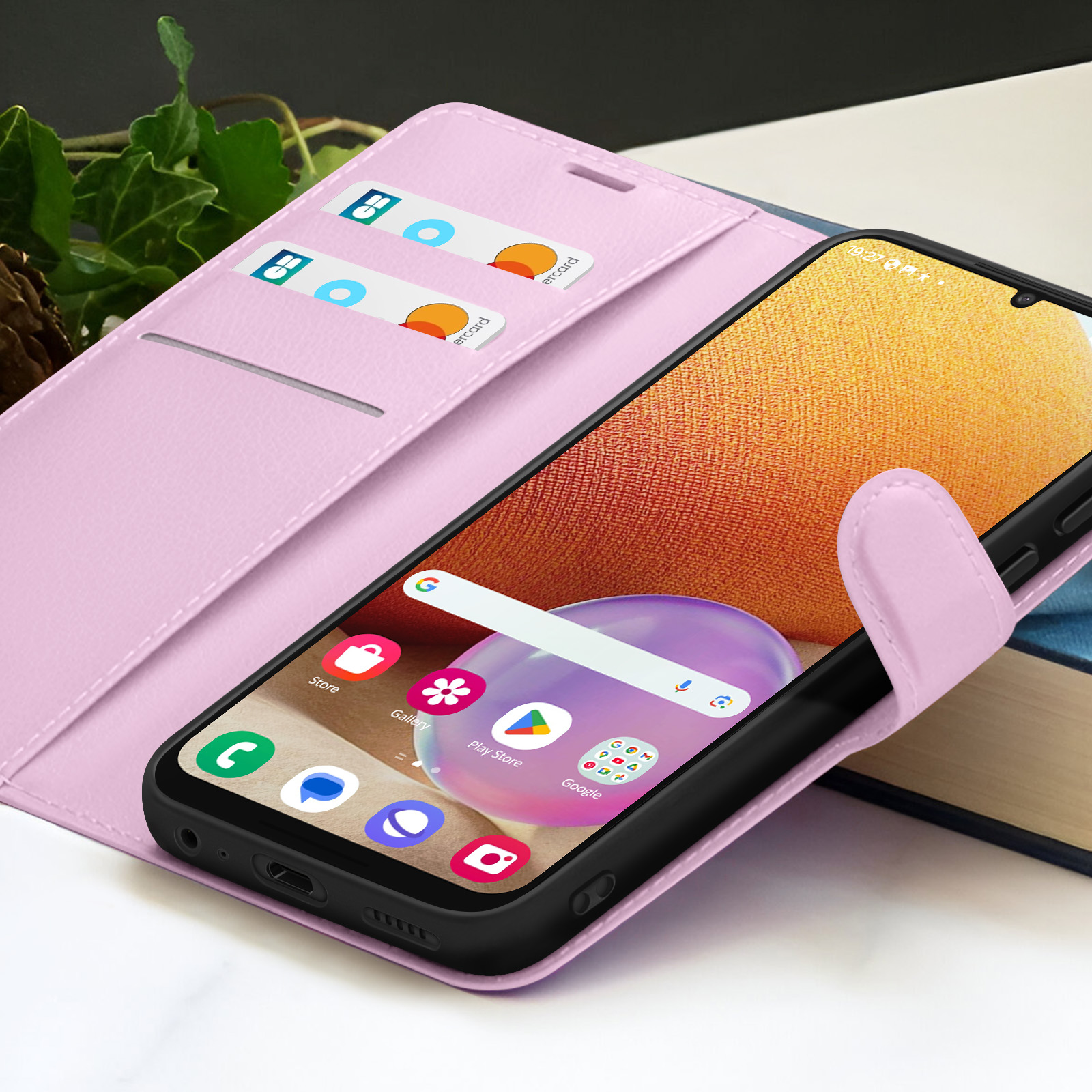 Roze telefoonhoesje met telefoon erin. Kaarten in de hoes. Telefoon toont pictogrammen op het scherm.