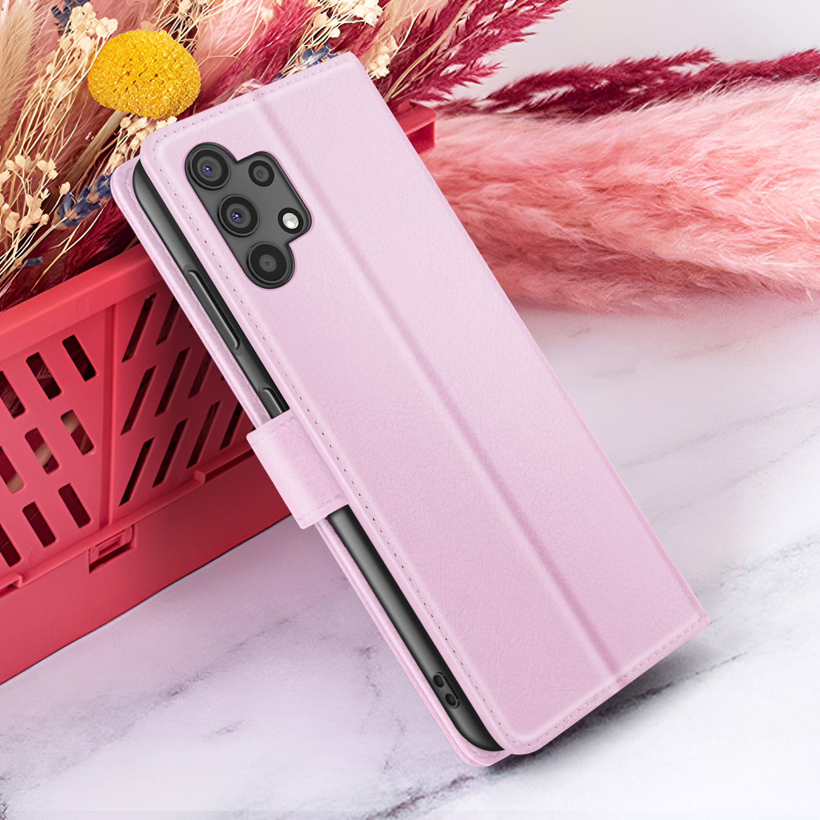 Roze telefoonhoesje met telefoon. Bloemen en een rode mand op de achtergrond. Marmeren oppervlak.