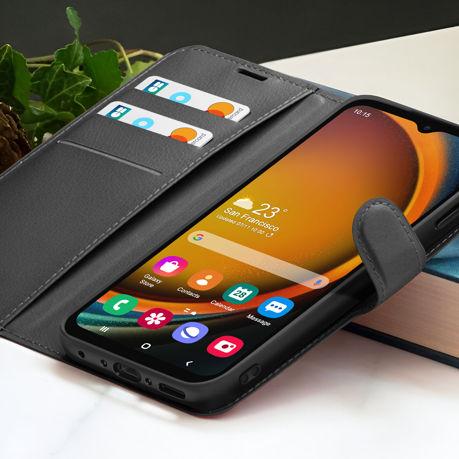 Een smartphone met een zwarte hoes toont pictogrammen. Het zit in een grijze leren portemonneehoes met kaarten. Het scherm toont 23 graden in San Francisco.