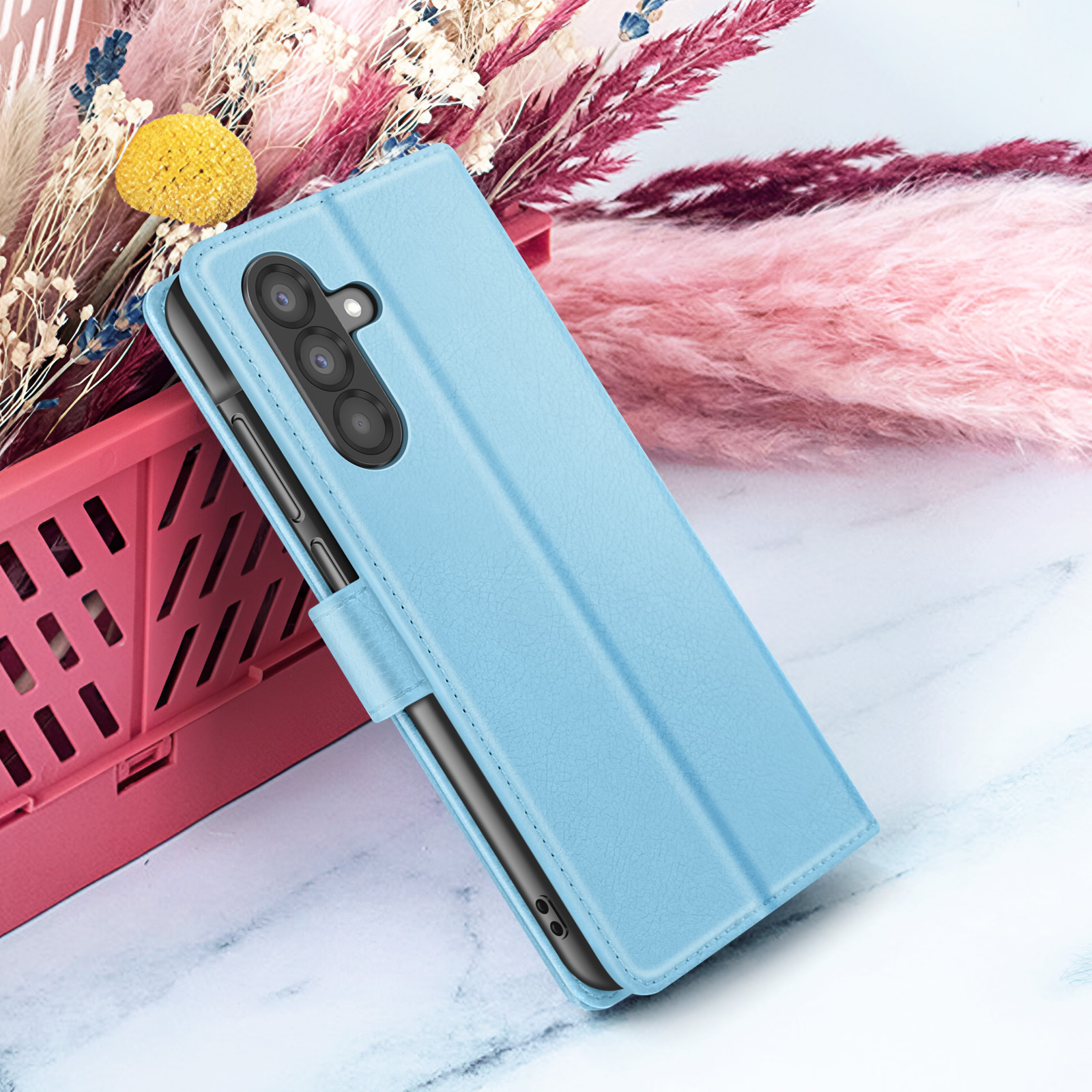 Een lichtblauwe telefoonhoes wordt weergegeven, met een telefoon erin. Roze en witte bloemen op de achtergrond.