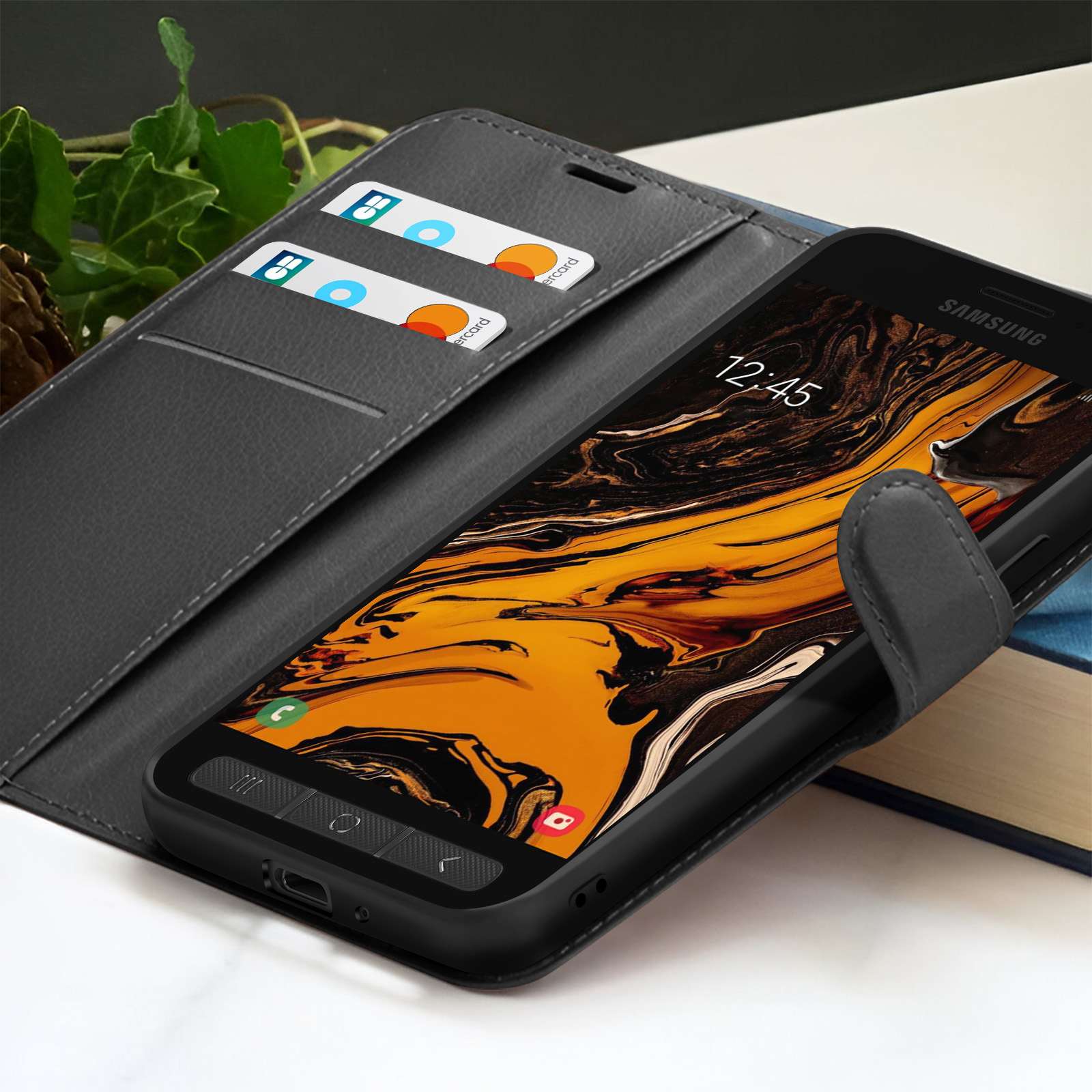 Een Samsung telefoon in een zwarte hoes met creditcards in de hoes. De weergegeven tijd is 12:45. De achtergrond is wazig.