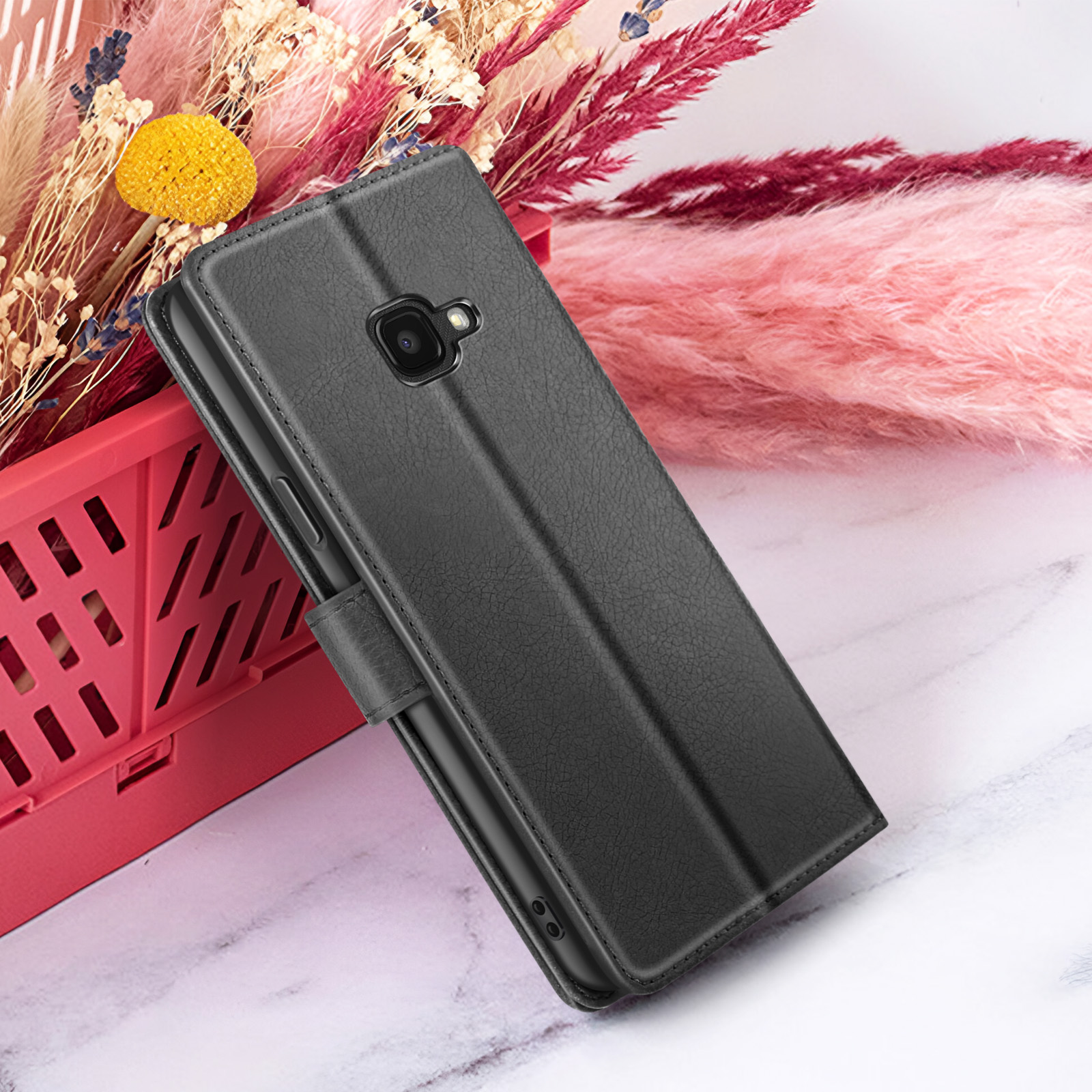 Een zwarte telefoonhoes wordt getoond, naast roze en rode bloemen. De hoes ligt op een marmeren oppervlak.