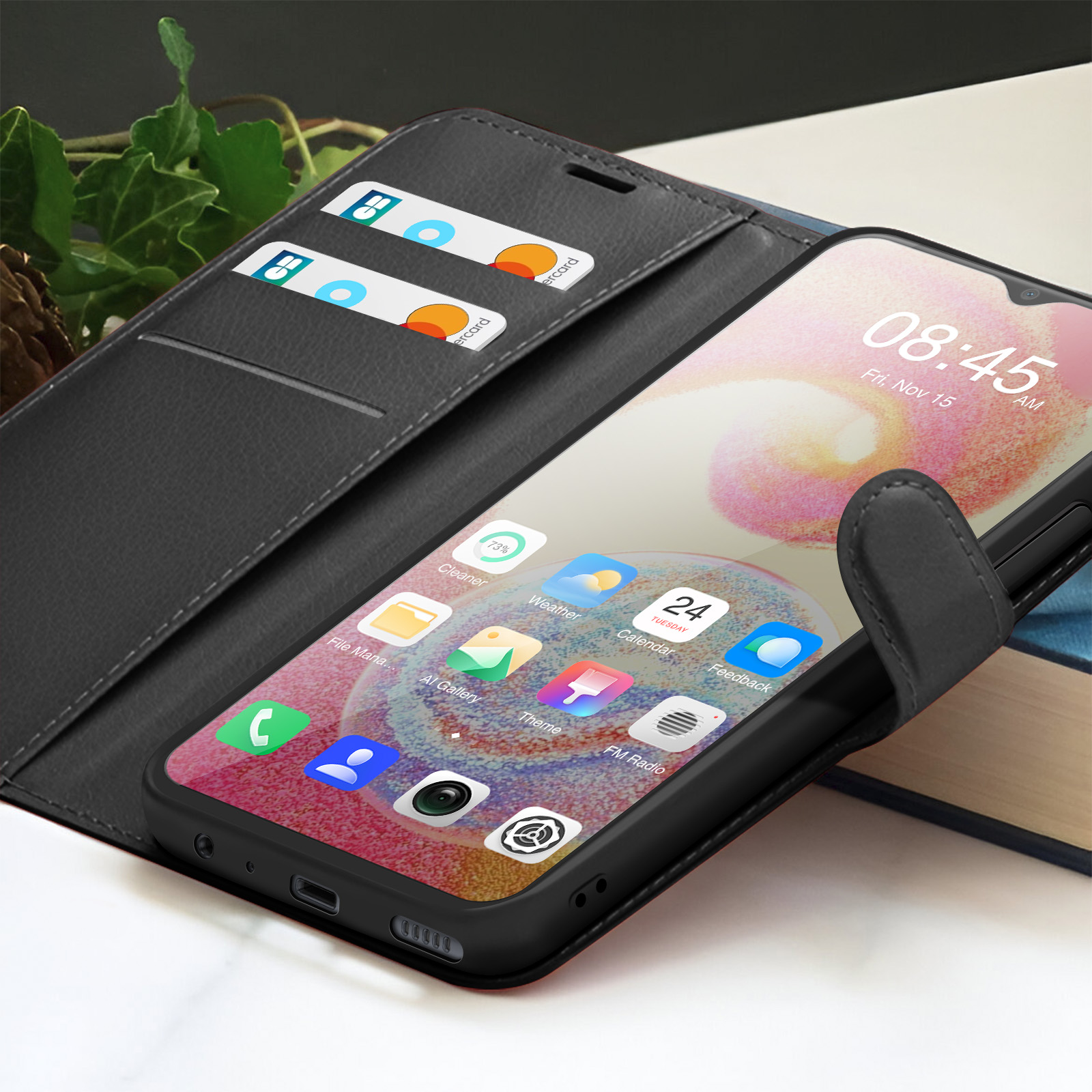 Smartphone in een zwarte hoes, met tijd en apps. Creditcards in een zakje. Achtergrond is bladeren en boeken.