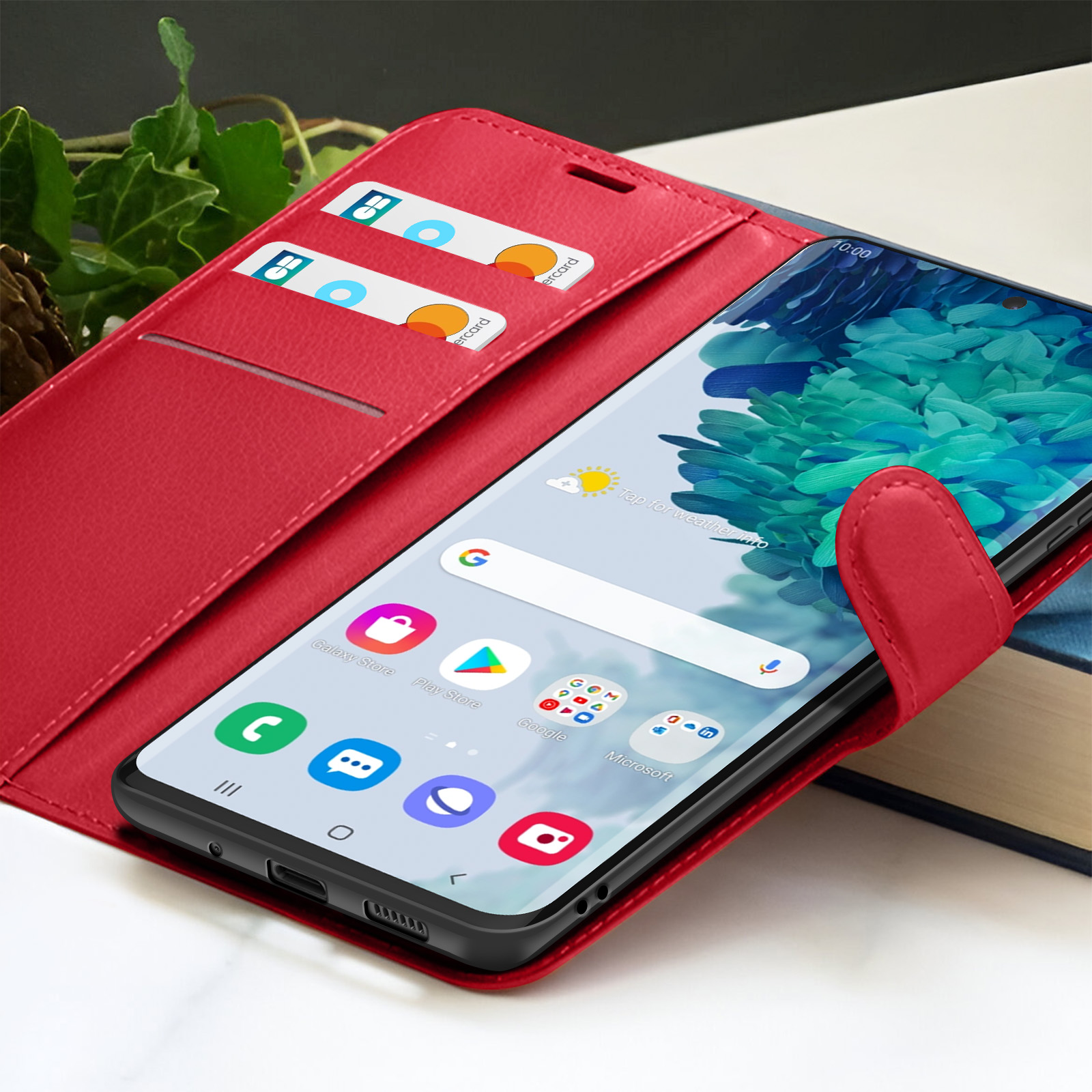 Een rode telefoonhoes met een smartphone die apps toont. Creditcards zichtbaar. Een boek op de achtergrond.