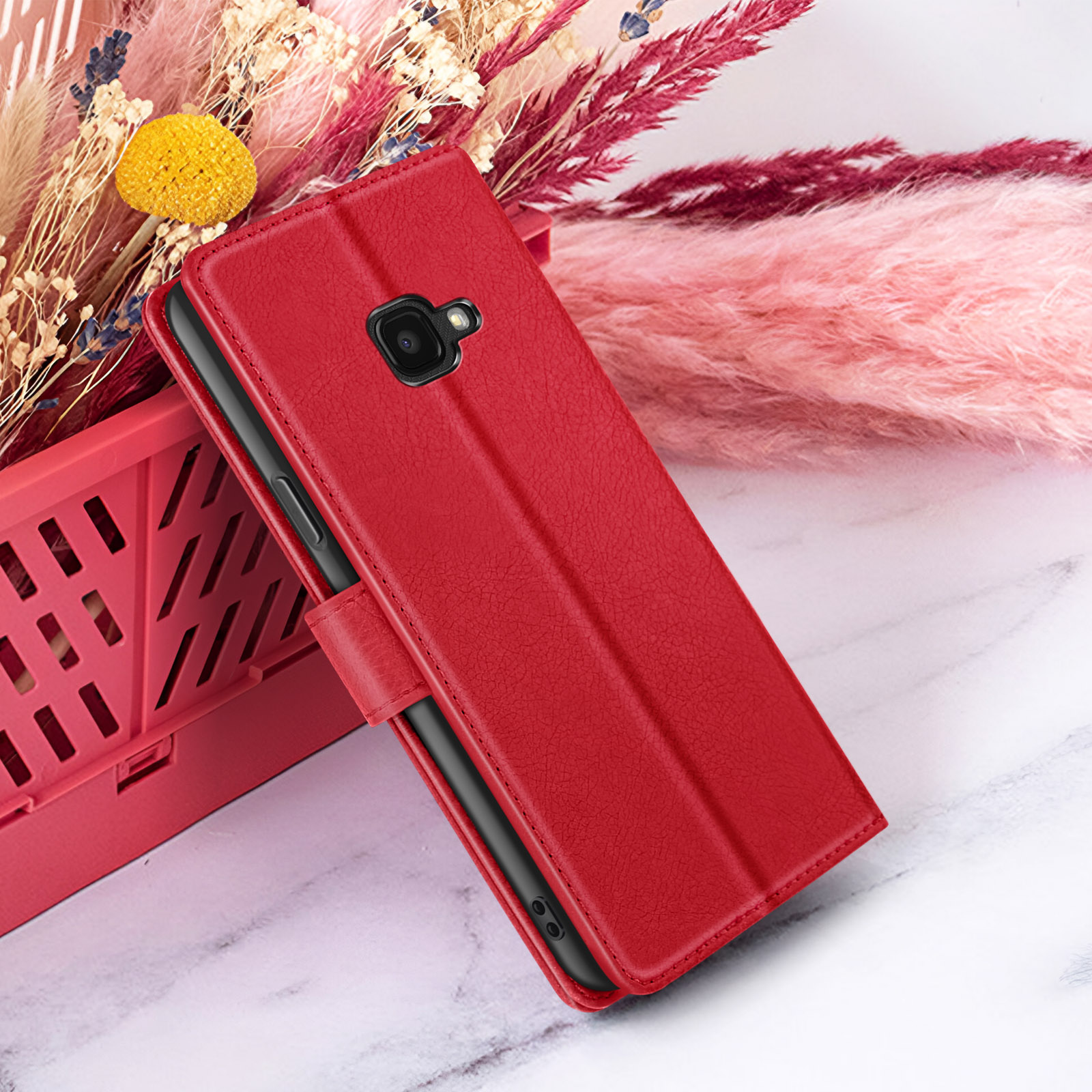 Étui de téléphone rouge avec téléphone à l'intérieur, contre fond floral, sur marbre blanc.