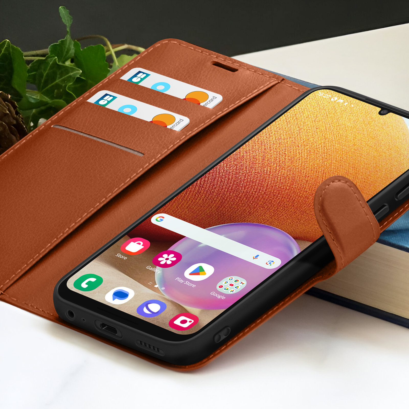 Een bruine telefoonhoes met een telefoon. De telefoon toont het startscherm. Twee creditcards in een sleuf.