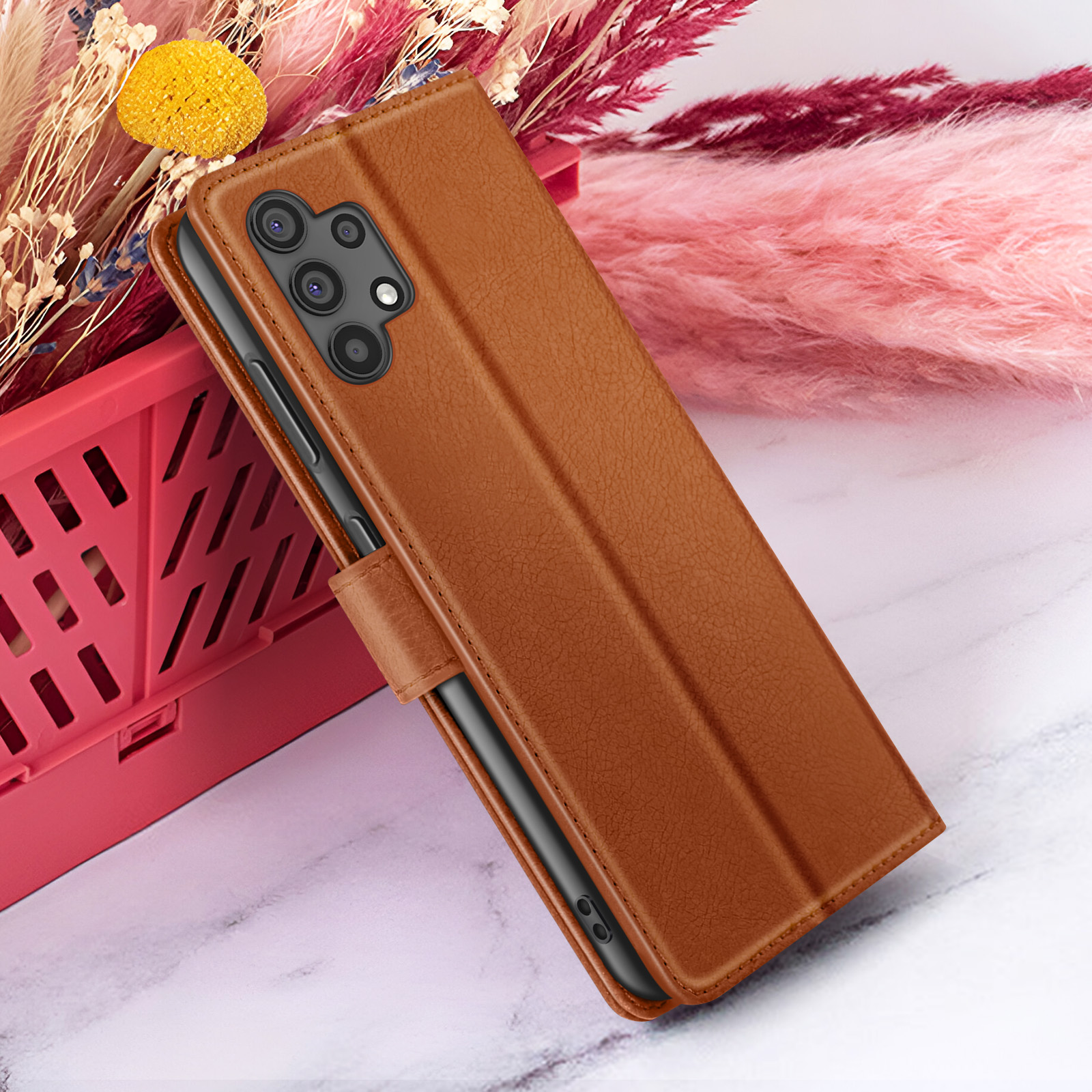 Een bruine lederen telefoonhoes op een marmeren oppervlak, met bloemen op de achtergrond.