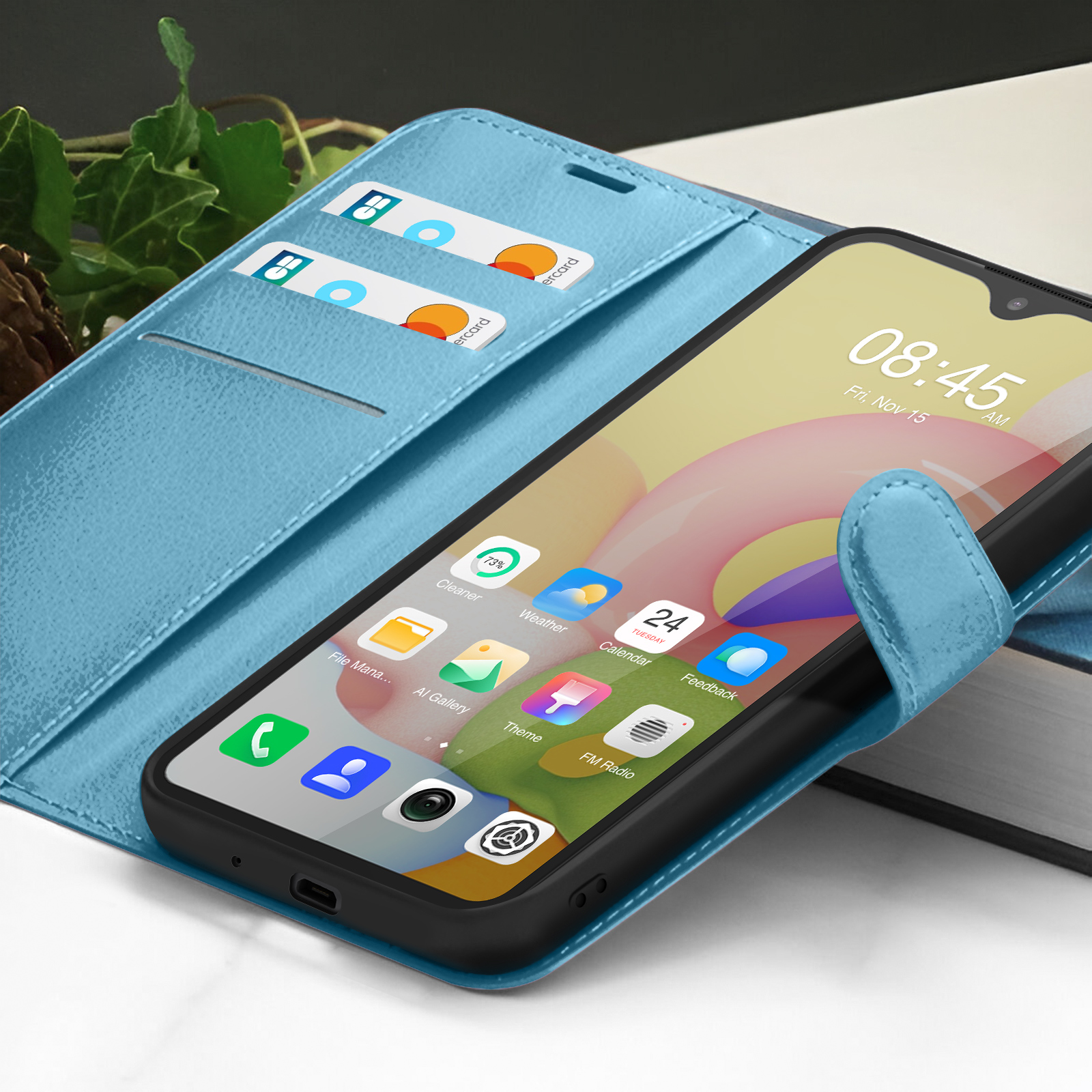Een smartphone in een lichtblauwe hoes. De tijd is 08:45 uur, vr. 15 nov. Creditcards zitten in de hoes.