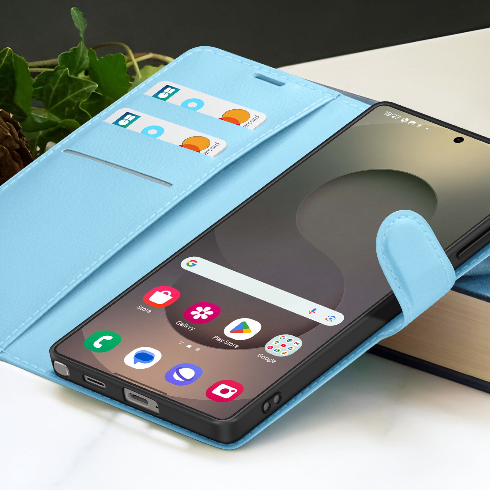 Een smartphone in een lichtblauwe hoes. De telefoon geeft app-pictogrammen weer. Twee creditcards zijn zichtbaar in de hoes.