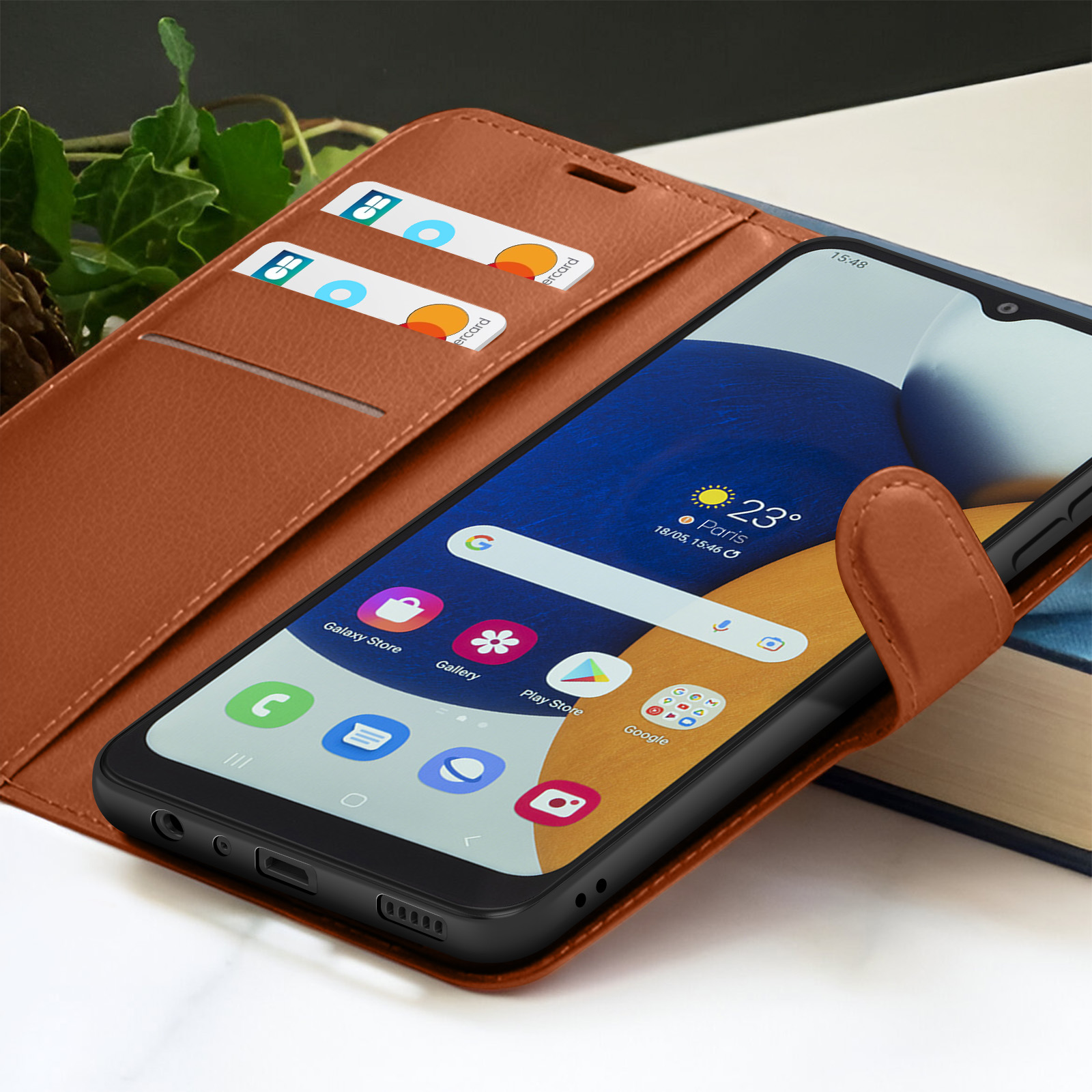 Un smartphone dans un étui en cuir marron. Des cartes de crédit sont dans l'étui. L'écran affiche des applications et l'heure.