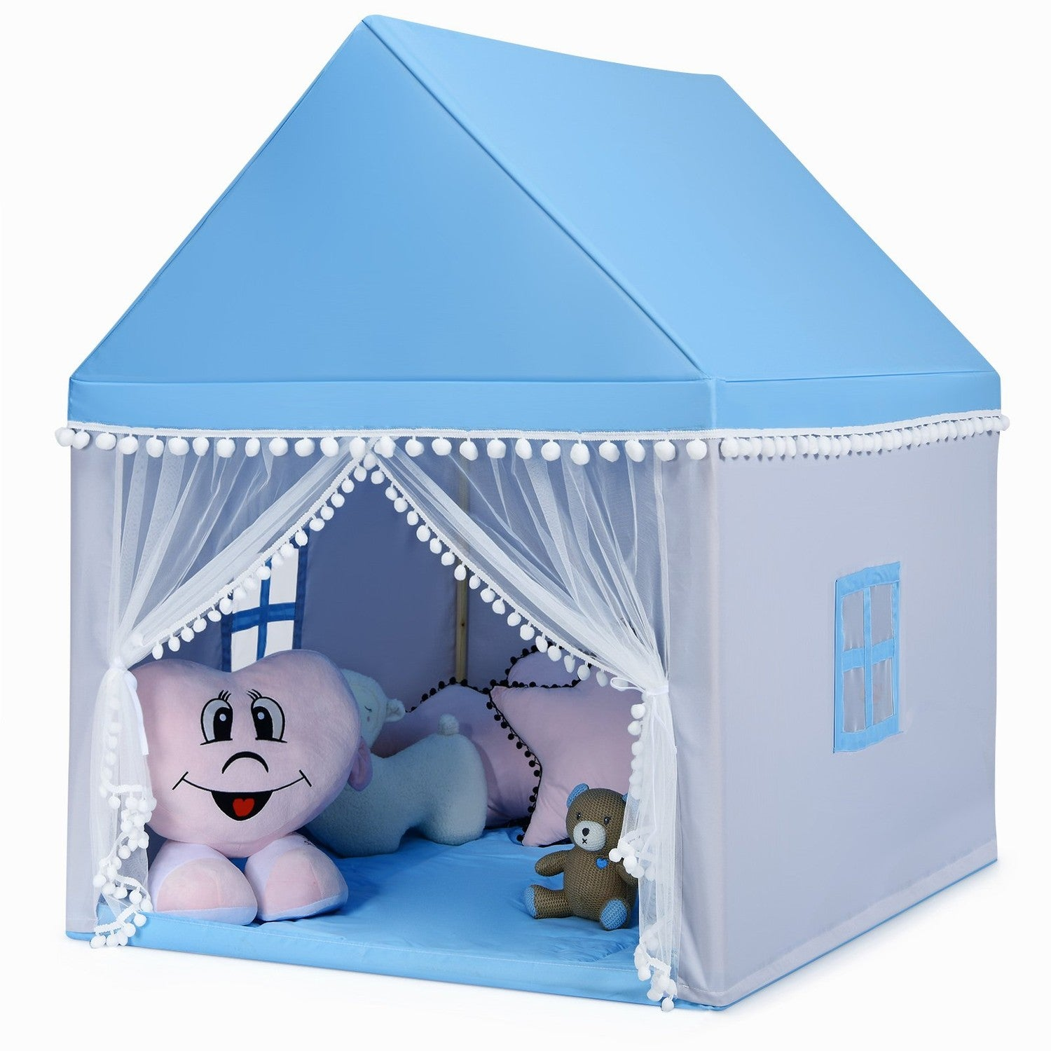 Una tienda de campaña para niños con techo azul y cortinas blancas. Dentro hay peluches, incluyendo un corazón sonriente, un oso y almohadas.
