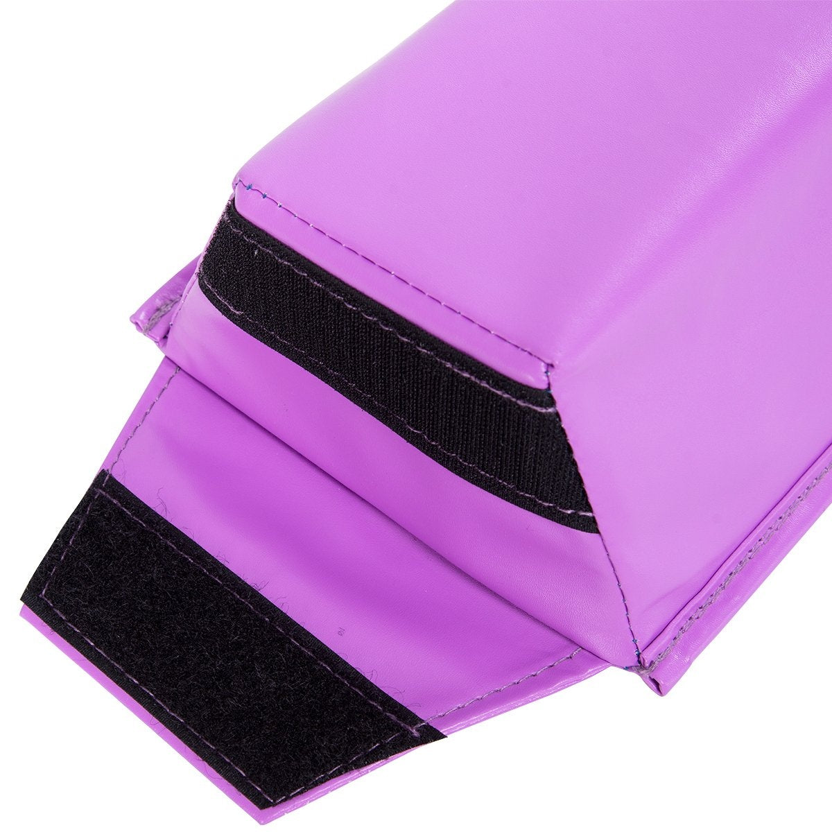 Primer plano de una colchoneta de gimnasia morada con correas de velcro negras. La colchoneta está doblada, mostrando sus ángulos. El fondo es blanco.