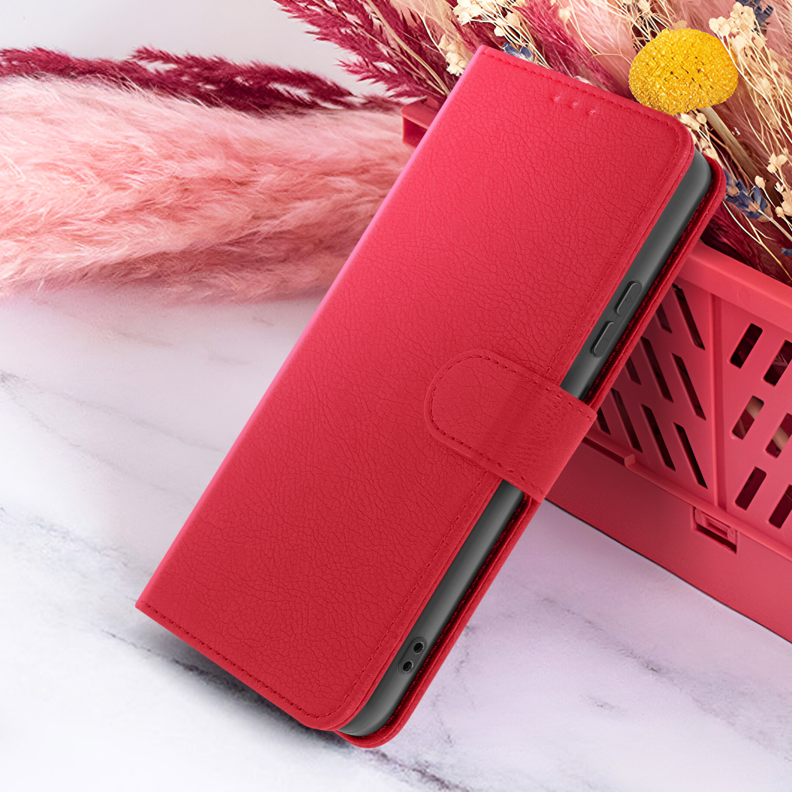 Rode telefoonhoes met flap, op een marmeren oppervlak met roze, rode en gele decoratieve elementen.