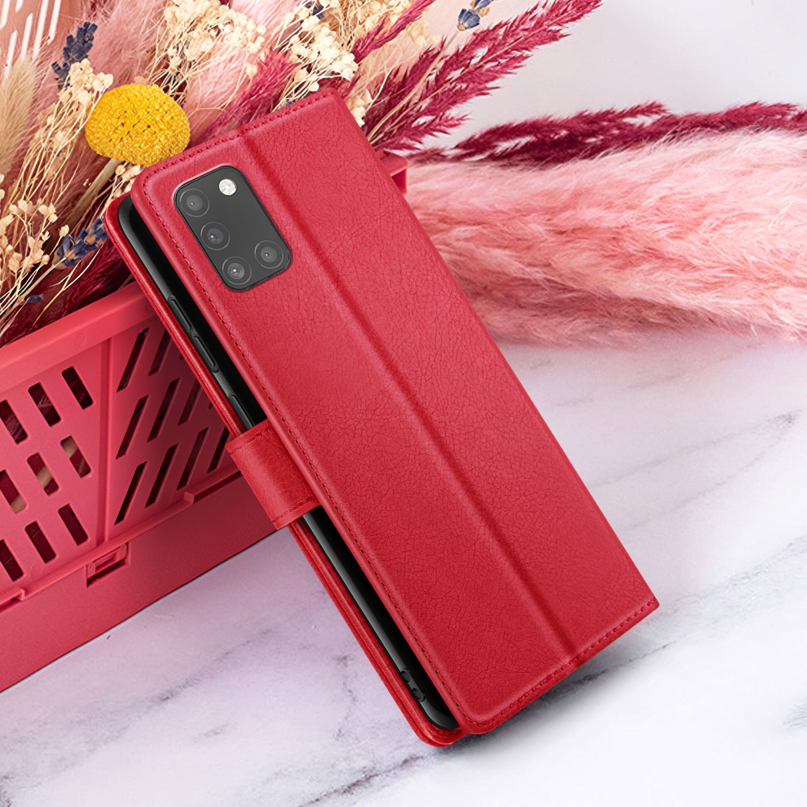 Un étui de téléphone rouge est ouvert, révélant un téléphone. Derrière, il y a des fleurs décoratives.