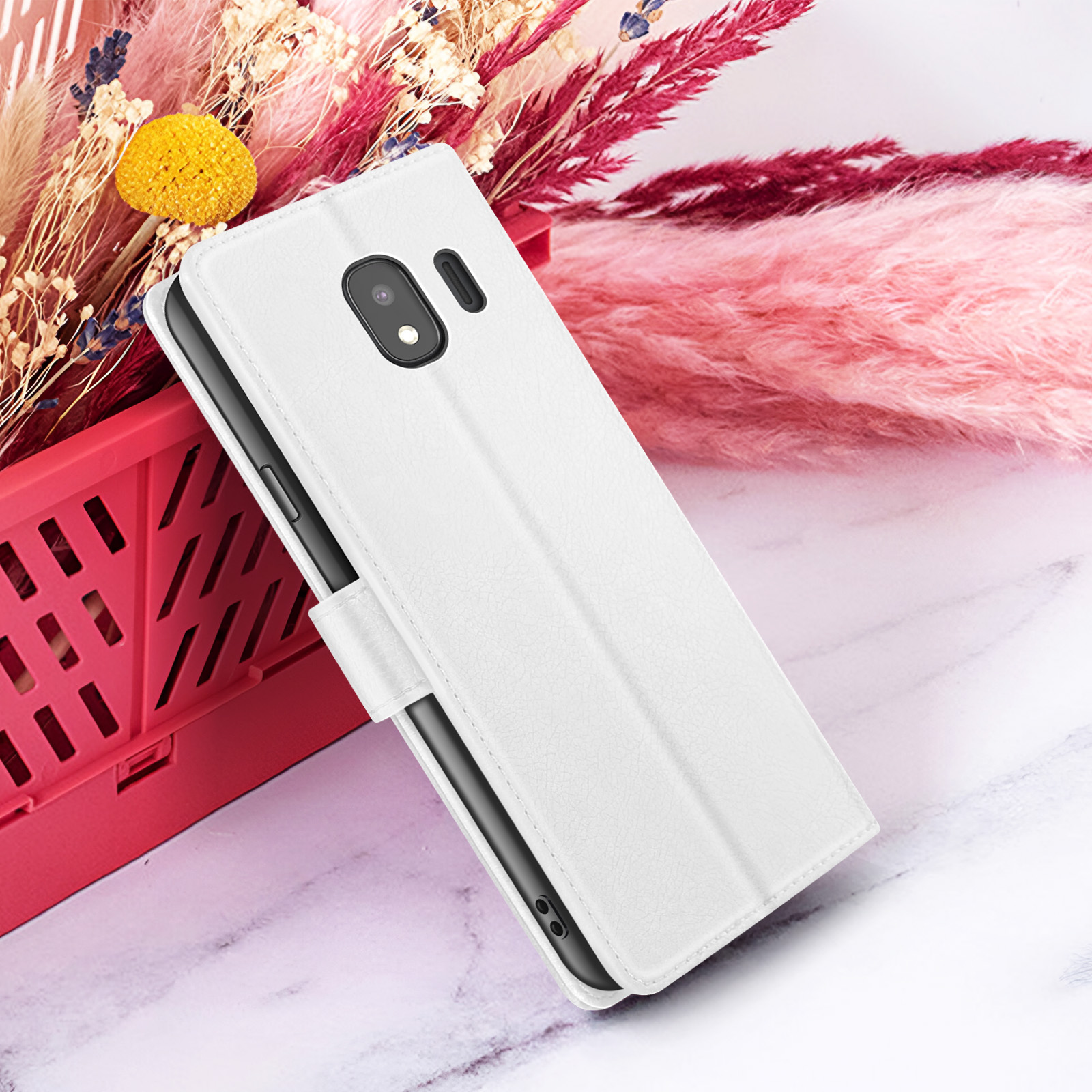 Een witte telefoonhoes is open en toont een telefoon. Het ligt op een marmeren oppervlak, met roze en rode bloemen erachter.