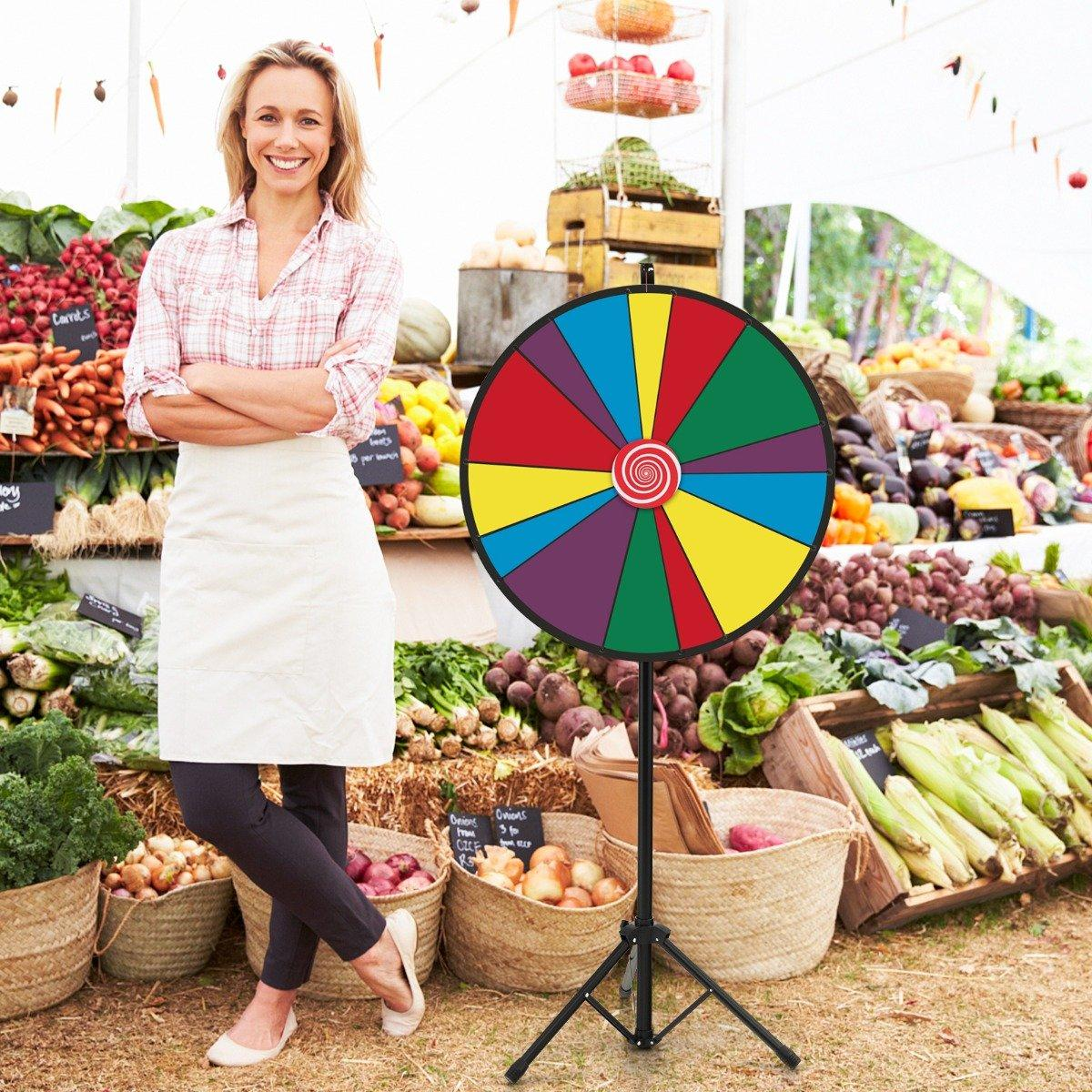Mujer en un mercado con una rueda de premios colorida. Cestas de verduras en el fondo. Lleva un delantal y sonríe.