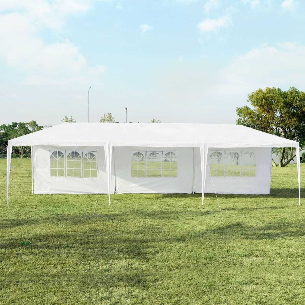 Una carpa blanca está instalada en un césped verde. La carpa tiene varias ventanas y un cielo despejado en el fondo.