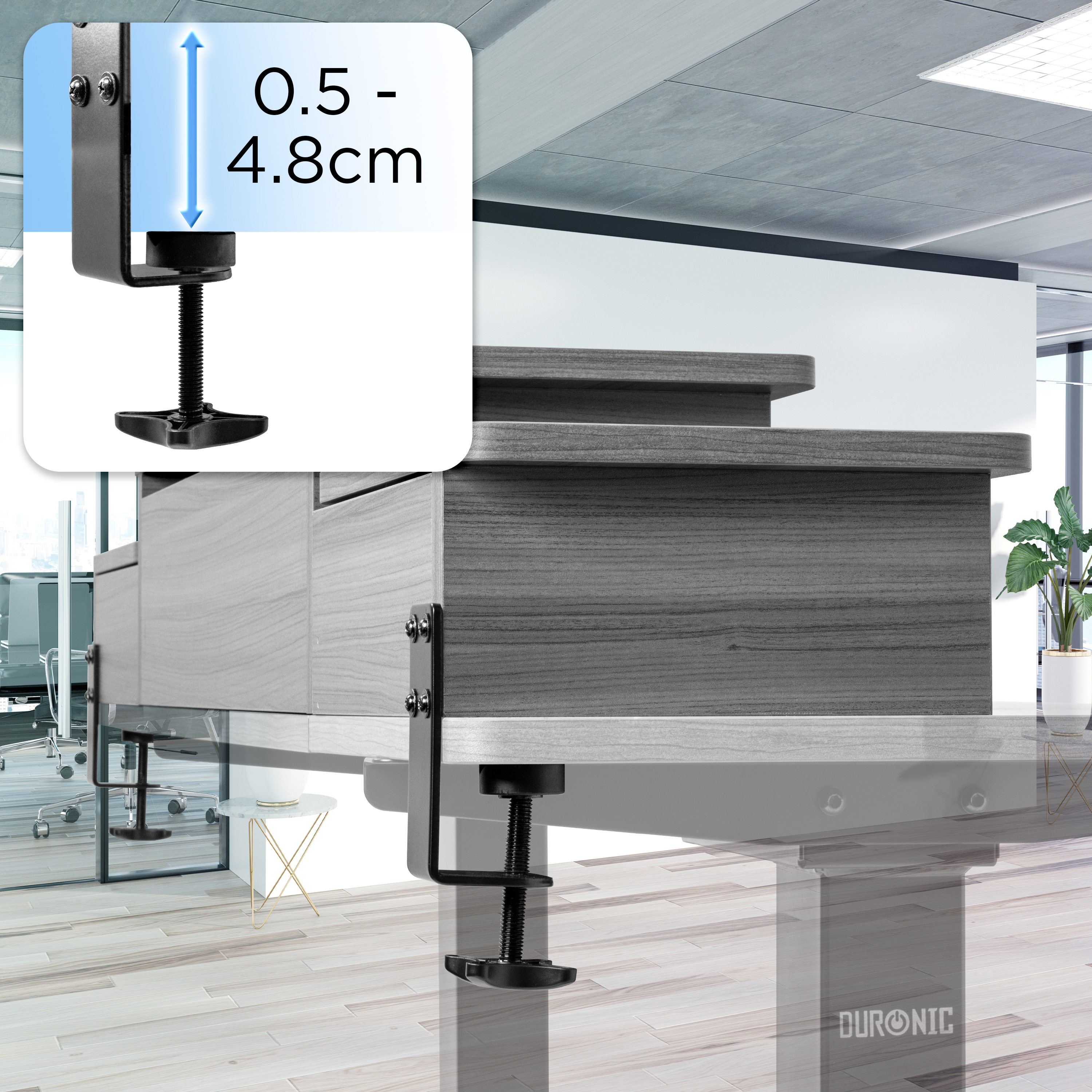 Eine schwarze Schreibtischklemme ist an einem Holzschreibtisch befestigt. Die Klemme ist höhenverstellbar. Büroumgebung im Hintergrund.