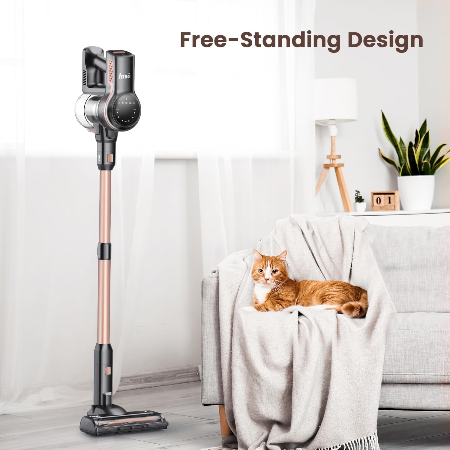 A cordless vacuum cleaner stands beside a sofa with a cat. Background: lamp, plant, and a calendar. The text says 'Free-Standing Design'.