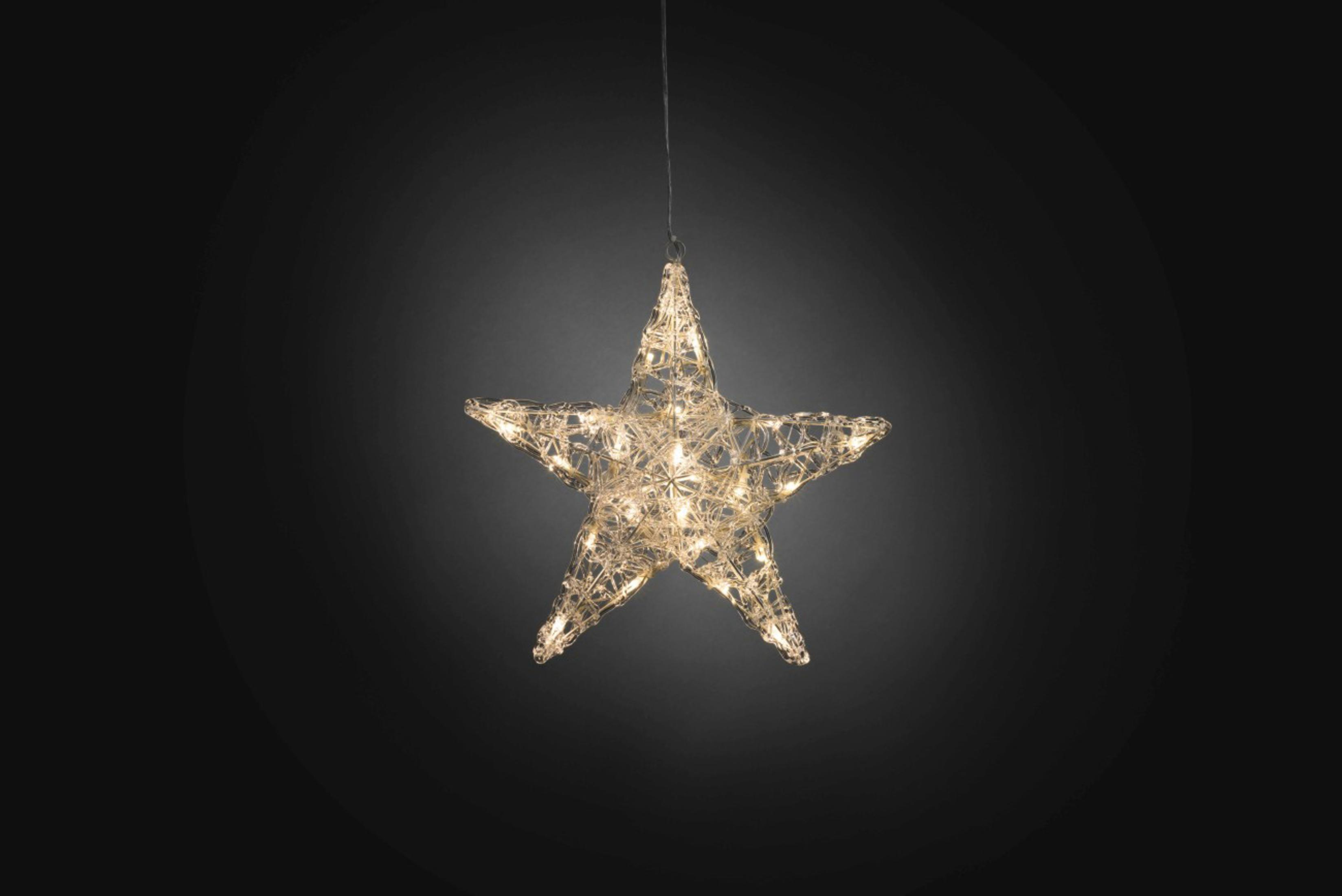 Una decorazione a forma di stella luminosa è appesa su uno sfondo scuro. La stella è fatta di filo e illuminata da piccole luci.