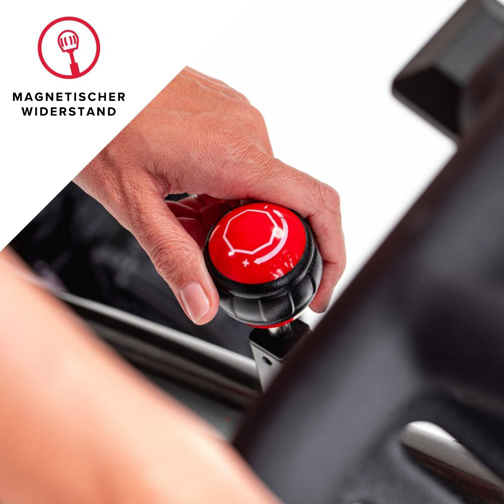 Eine Hand justiert einen roten Knopf mit einem weißen Sechseck. Der Knopf ist Teil eines schwarzen Mechanismus auf weißem Hintergrund.
