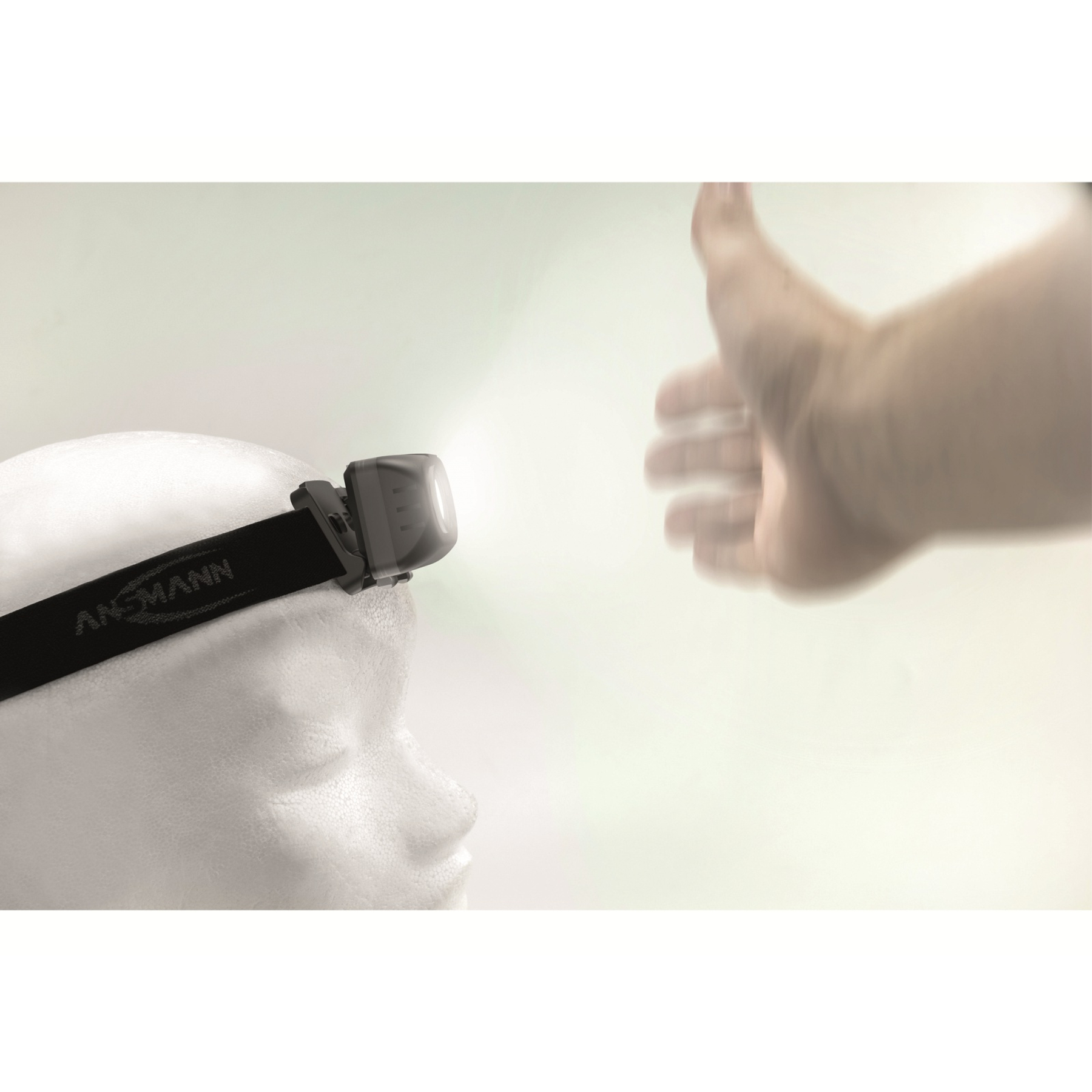 Głowa z czołówką i gestem kciuka w górę. Latarka jest włączona, a tło jest rozmyte.