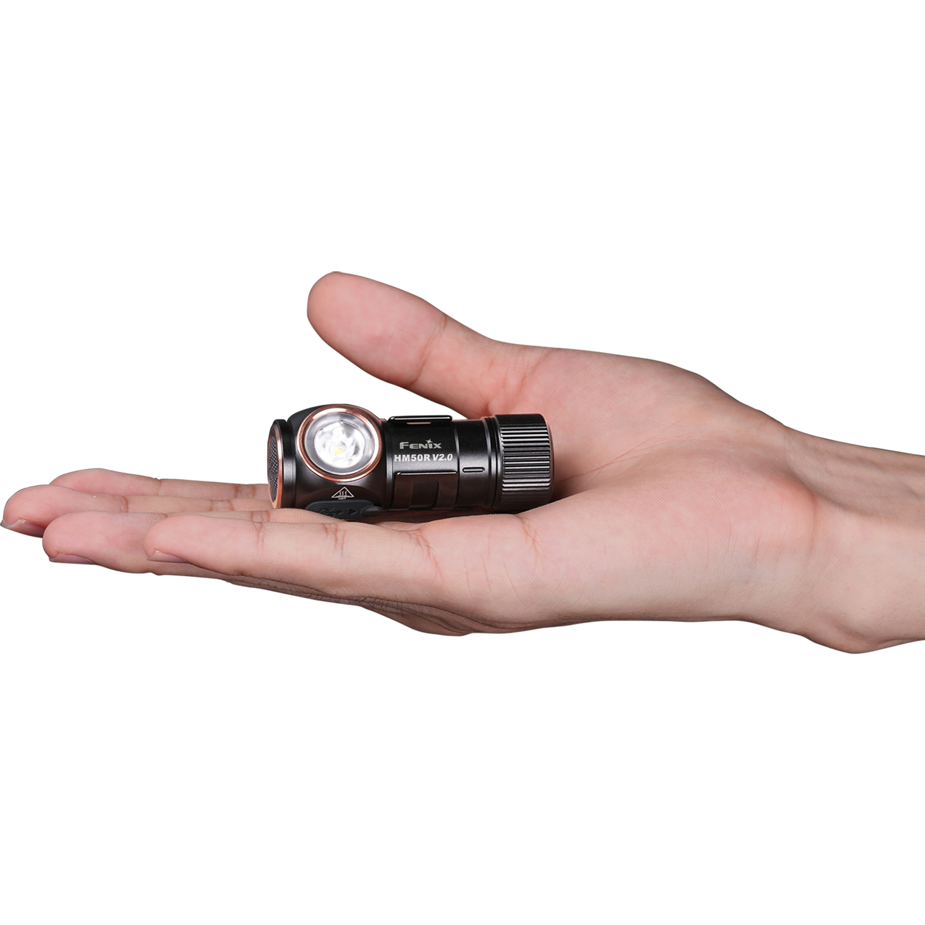 Une lampe frontale noire Fenix HM50R V2.0 est tenue dans une main humaine, sur fond blanc. La main est ouverte.