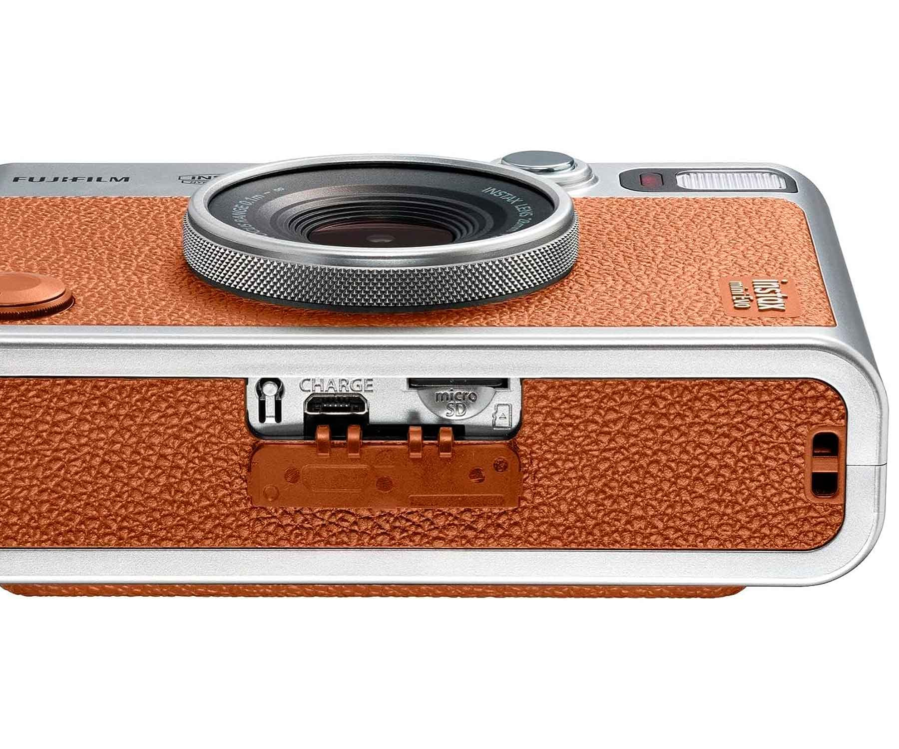 Nahaufnahme einer Kamera mit brauner, lederähnlicher Textur. Sie hat ein silbernes Objektiv und Ladeanschlüsse.