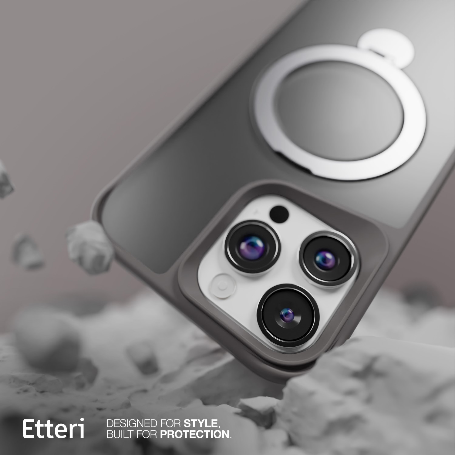 Una custodia grigia per telefono con supporto ad anello. Sono visibili tre lenti della fotocamera. La custodia è su una superficie rocciosa bianca.