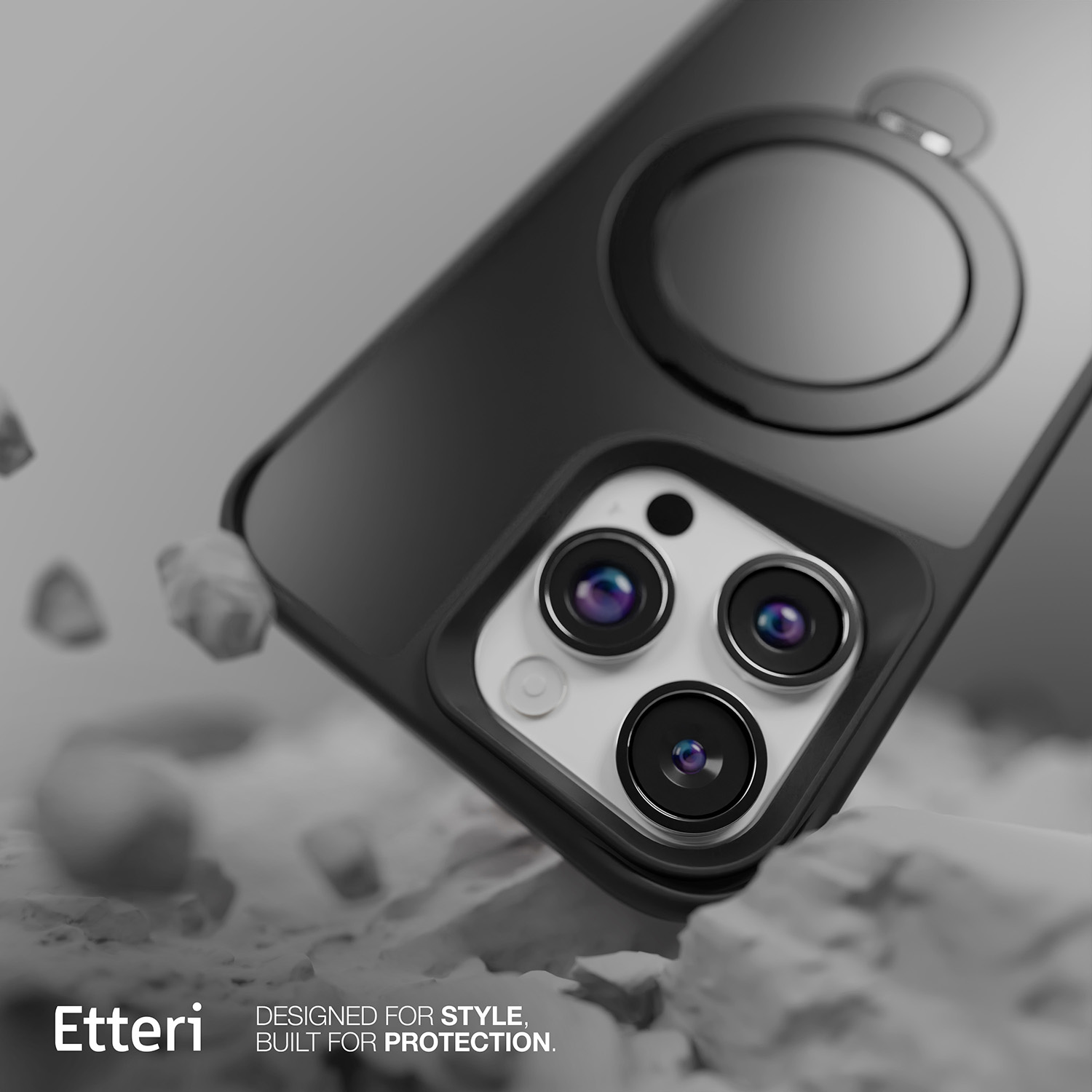Una custodia nera per telefono con tre lenti della fotocamera è appoggiata su una superficie strutturata e chiara. La custodia ha un anello.