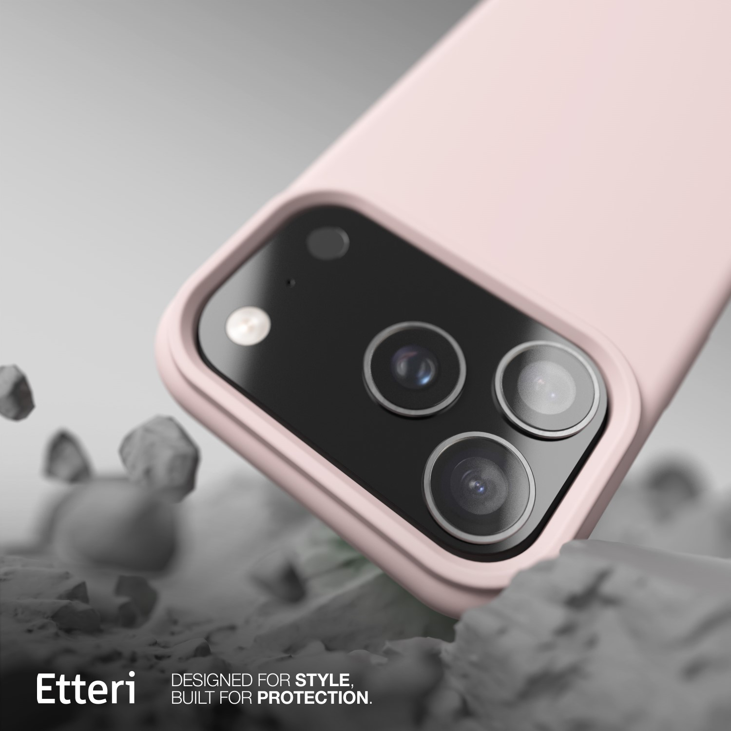 Primo piano di una custodia rosa per telefono con modulo fotocamera nero. La custodia è su una superficie grigio chiaro con forme simili a pietre.