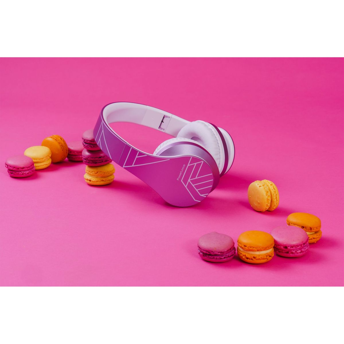Ein pinkfarbener Kopfhörer mit weißen Akzenten neben bunten Macarons. Der Hintergrund ist einfarbig pink.