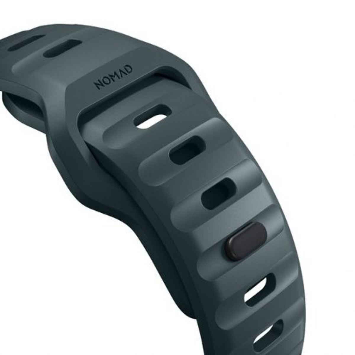 Primer plano de una correa de reloj gris oscuro con la palabra 'NOMAD'. Tiene agujeros rectangulares y un botón negro. Fondo blanco.