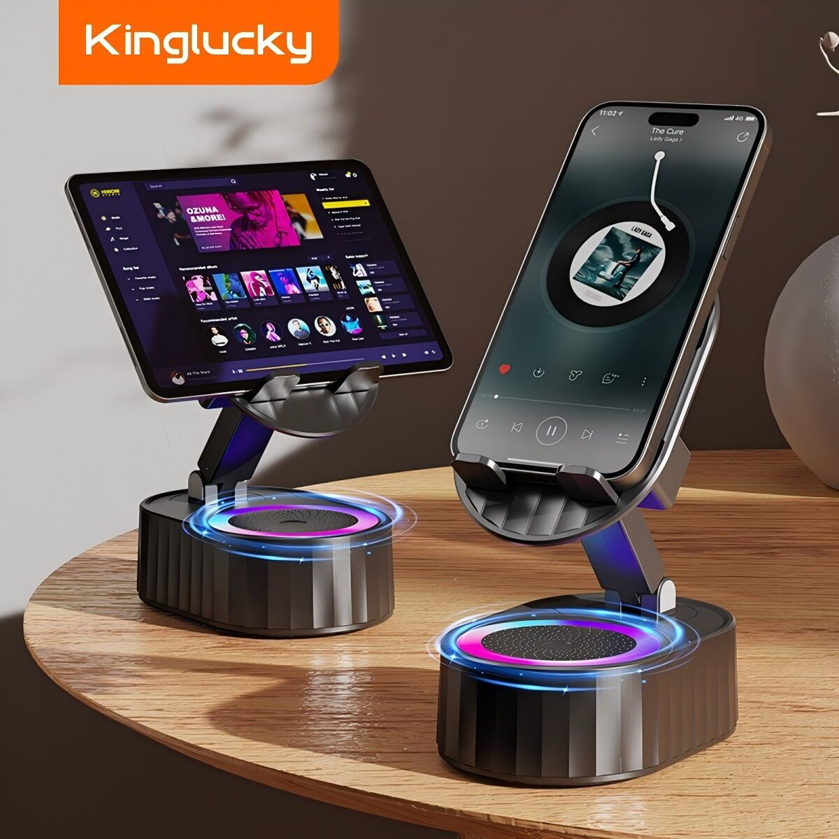 Zwei schwarze Telefonständer mit leuchtenden Sockeln. Ein Tablet und ein Telefon zeigen Musik an. Ständer stehen auf einer Holzoberfläche.