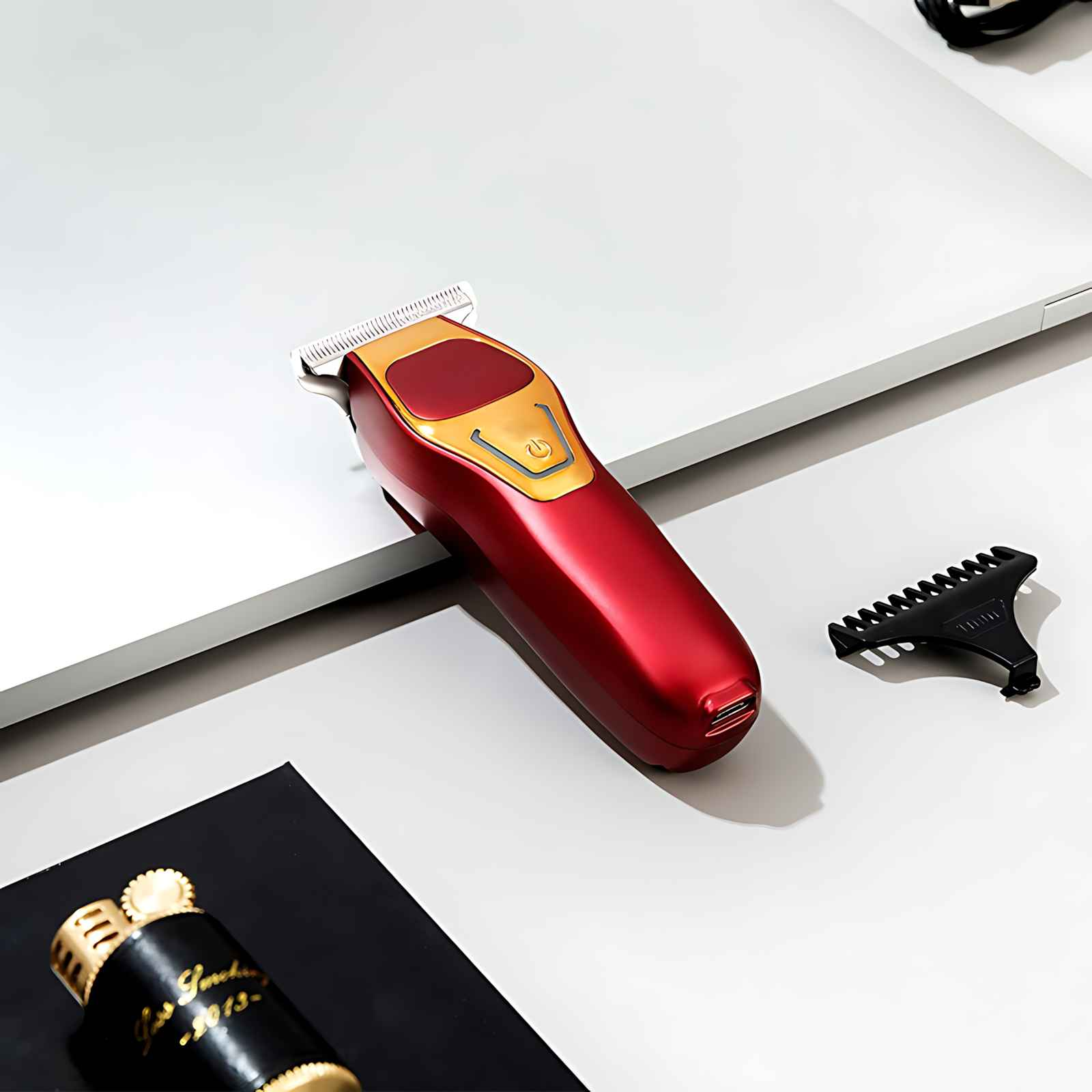 Ein roter und goldener Haarschneider liegt auf einer weißen Oberfläche, mit einem schwarzen Aufsatz und einem schwarzen Feuerzeug.