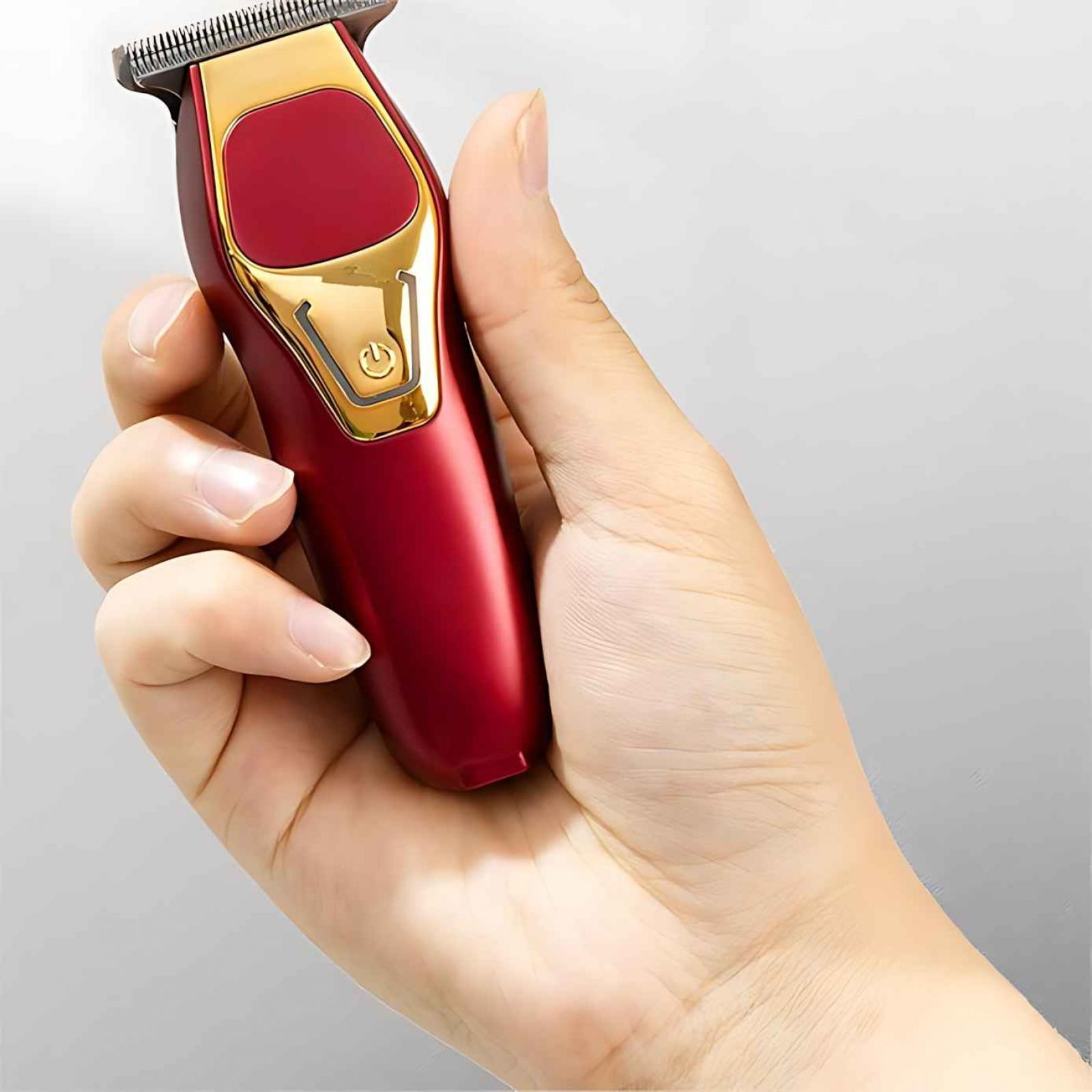 Eine Hand hält einen rot-goldenen Haarschneider. Die Klinge des Trimmers befindet sich oben.
